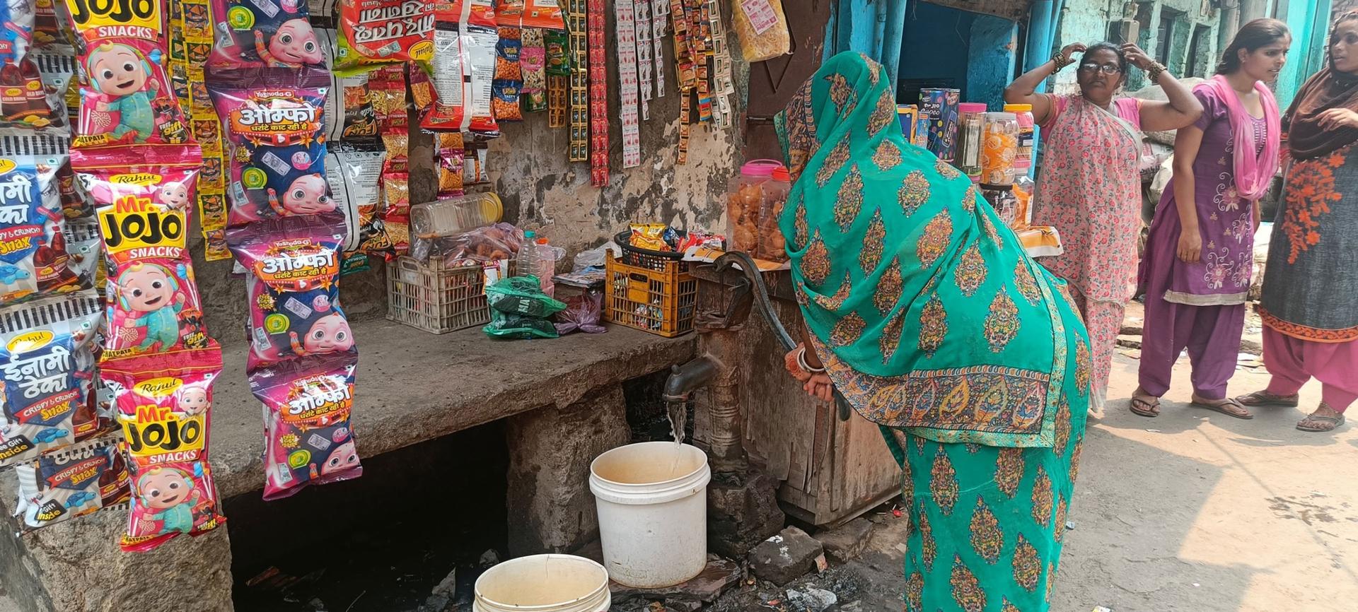 A woman draws water from a common pump in the slum next to a landfill in northern Delhi. 