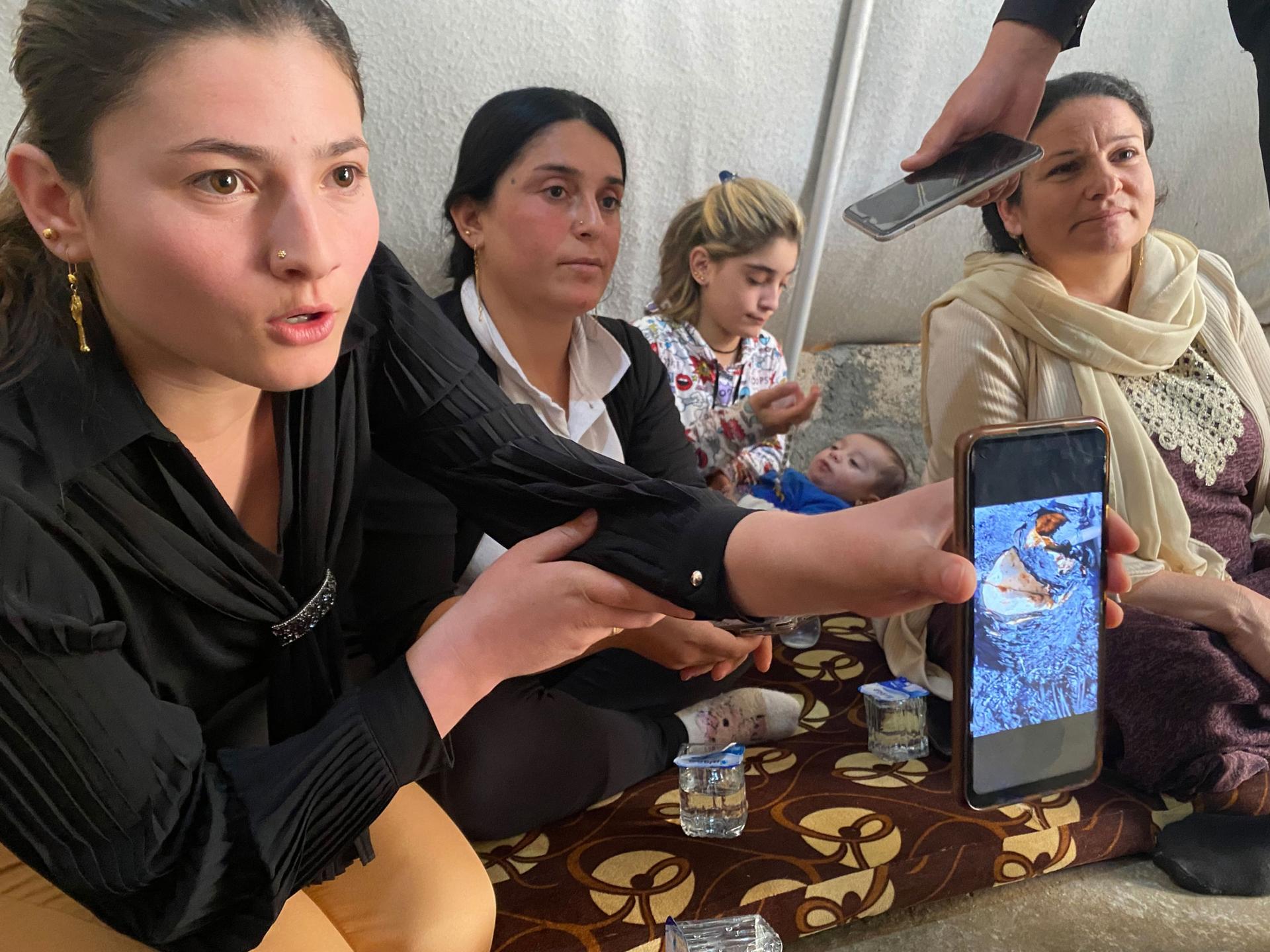Iman Jalal, 18, holds up a picture of her family’s burned tent at Sharya camp. Her family has returned to the displacement camp despite fears of another fire after recent fighting in Sinjar. 