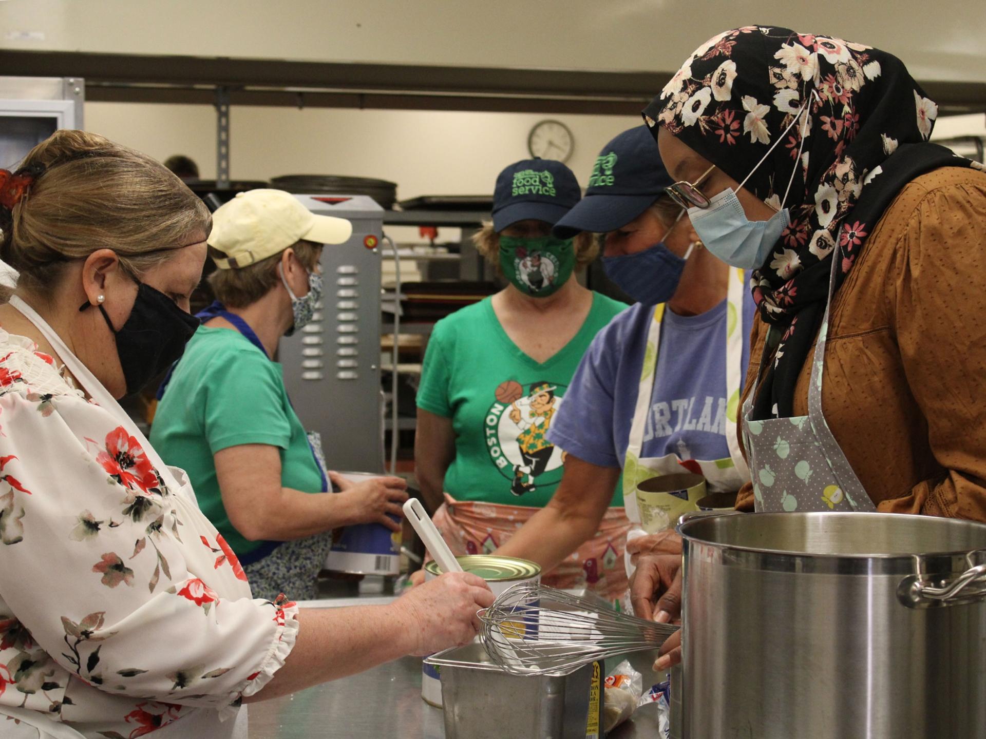 Khadija Ahmed, right, shows Portland Public Schools’ Food Service Director Jane McLucas how to make a sweet grits pudding, while district food service staff look on.