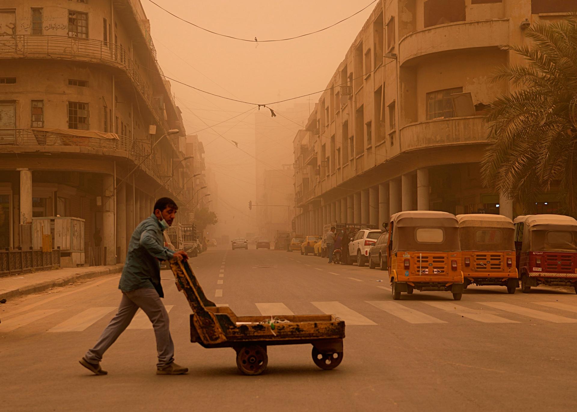 A man pushes a cart during a sandstorm in Baghdad, Iraq, Monday, May 23, 2022. 