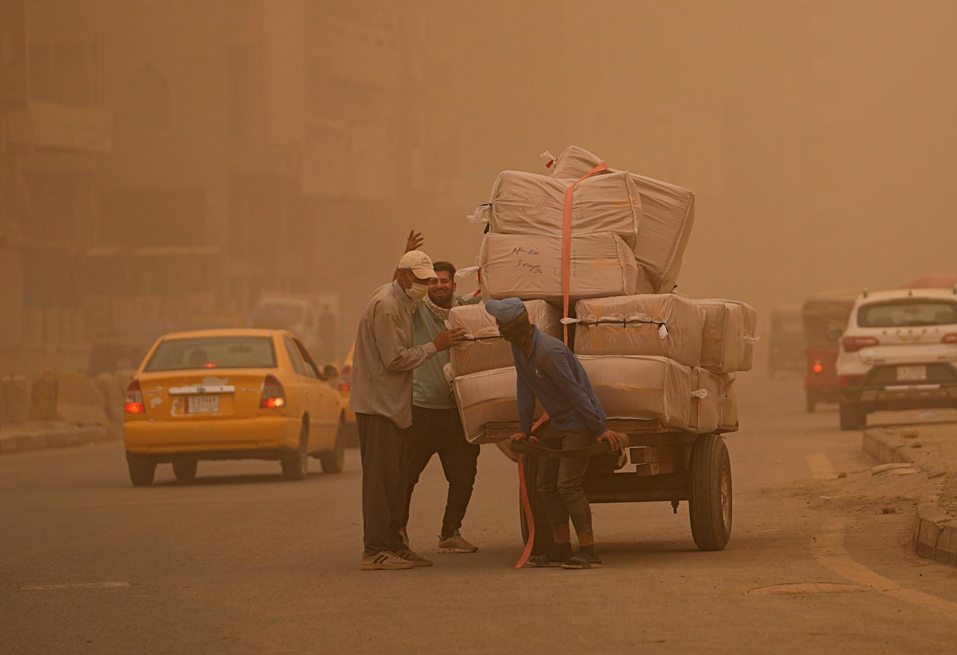 People push a cart during a sandstorm in Baghdad, Iraq, Monday, May 23, 2022.