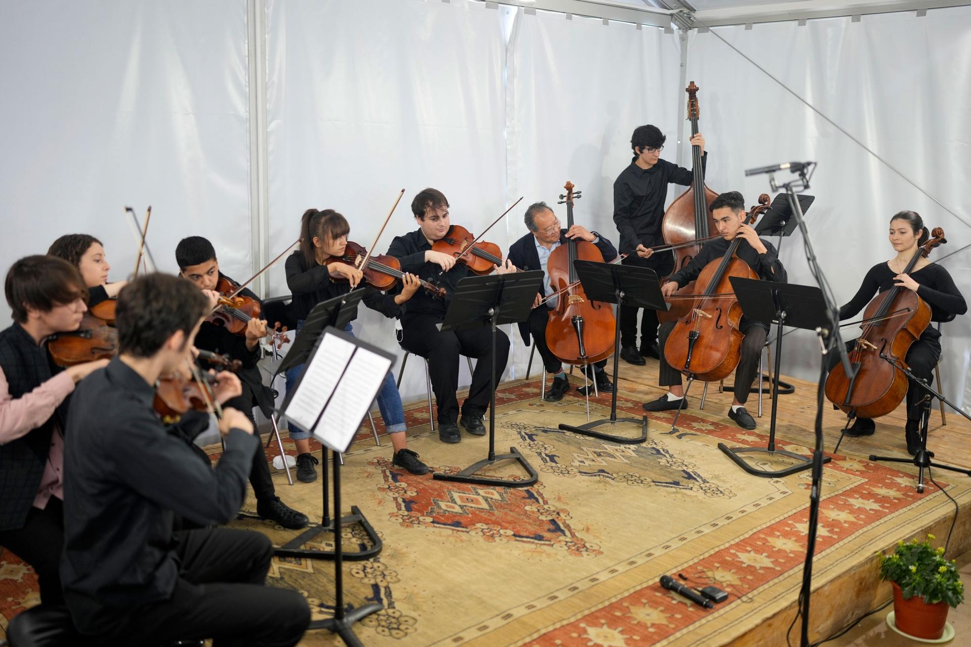 World renowned US cellist Yo-Yo Ma, 4th right, plays with Portuguese and Afghan music students at the Music School of the National Conservatory in Lisbon, Tuesday, March 29, 2022. 