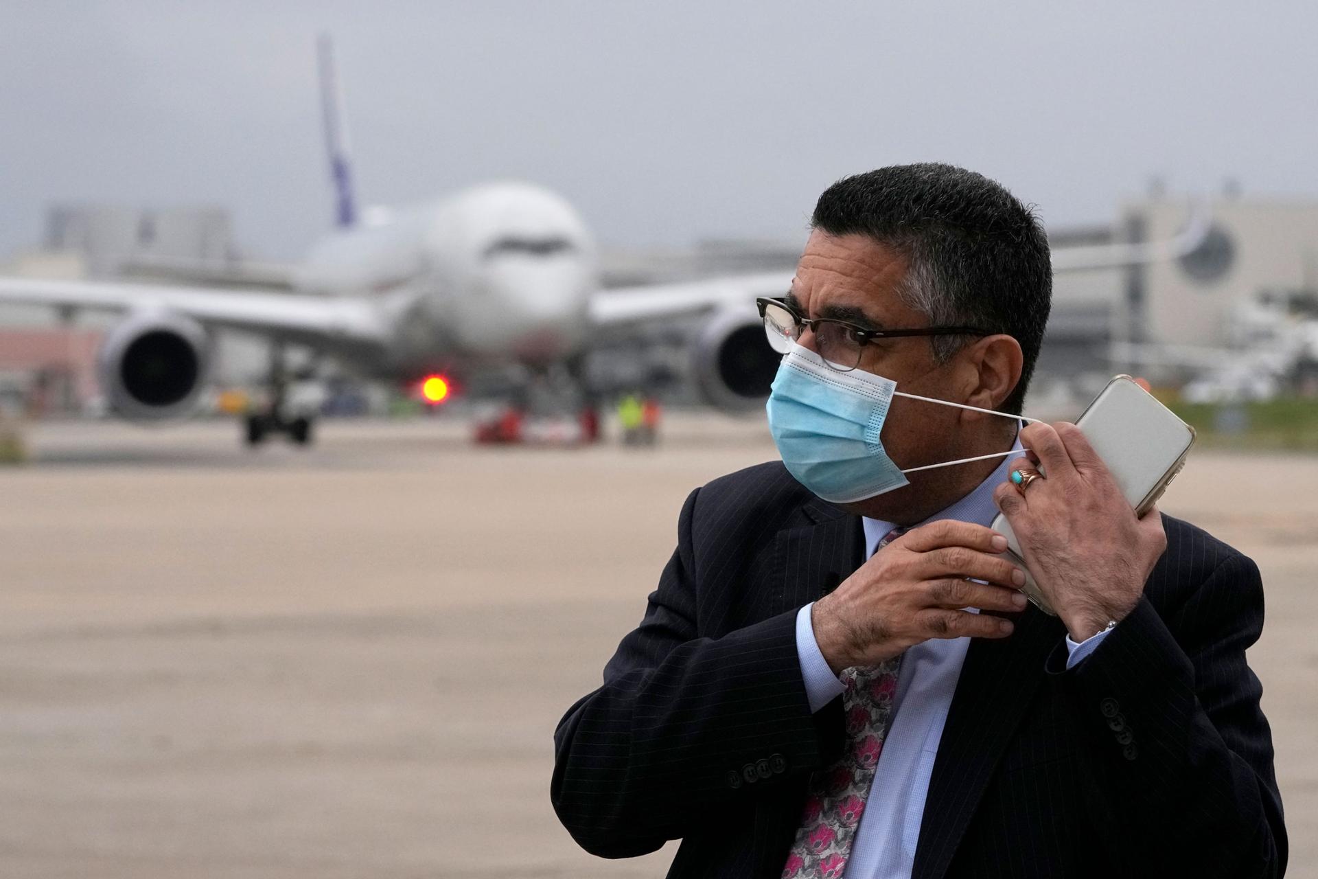 Ahmad Naser Sarmast, founder and director of the Afghanistan National Institute of Music, puts on his face mask as an airplane arrives at Lisbon military airport bringing music students, faculty members and their families from Afghanistan, Monday, Dec. 13