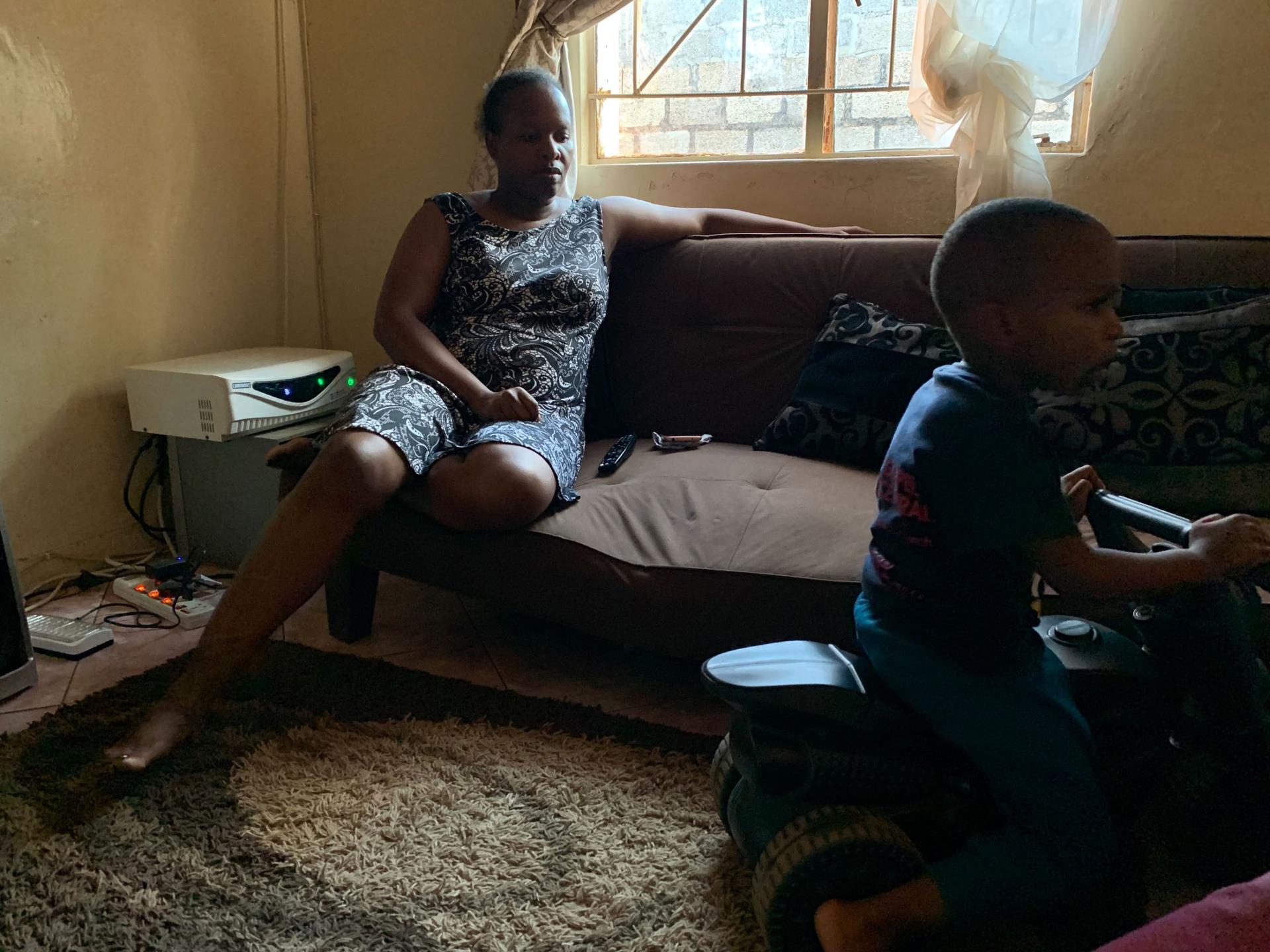 Nala Phiri relaxes on the couch while watching her son Sangu play in their living room. She first noticed symptoms of multiple sclerosis soon after Sangu was born in 2016. 