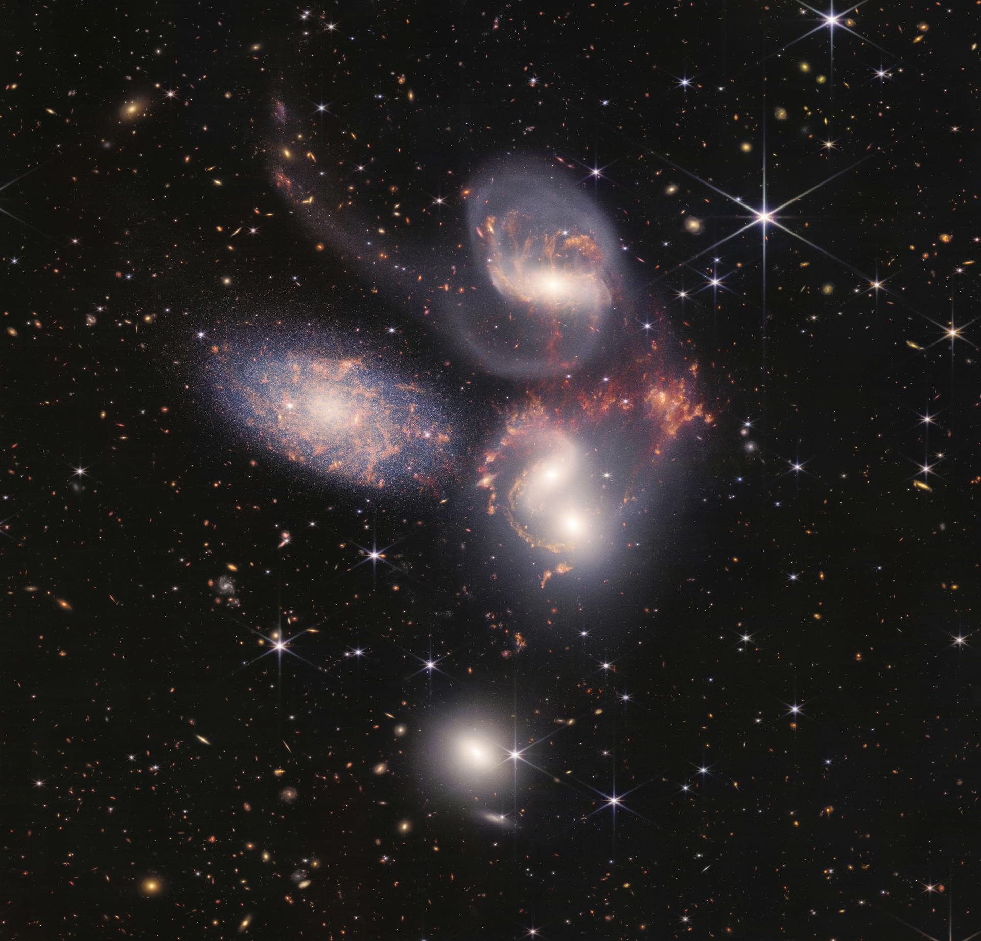 This image shows Stephan's Quintet, a visual grouping of five galaxies captured by the Webb Telescope's Near-Infrared Camera (NIRCam) and Mid-Infrared Instrument (MIRI)