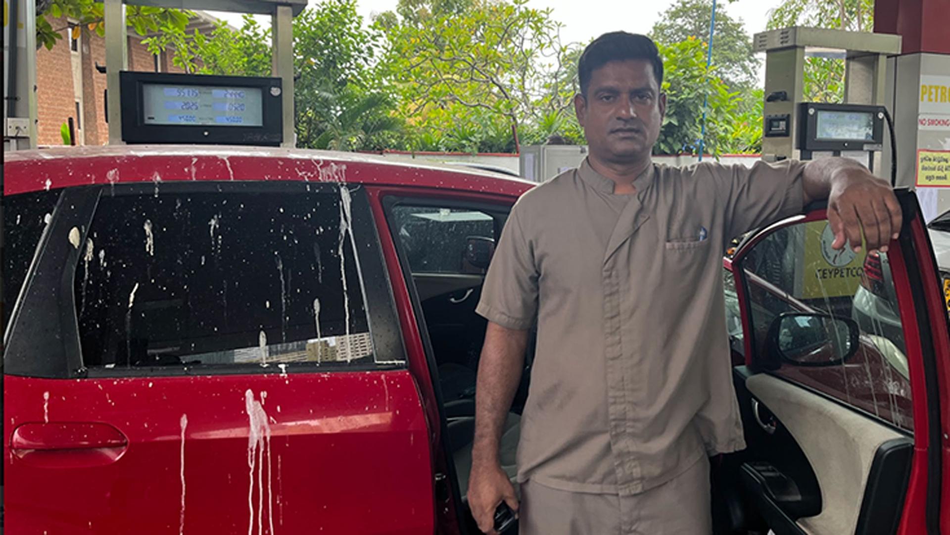 Hotel driver Kalum Jayantha stands next to his car at a gas pump in Colombo, Sri Lanka