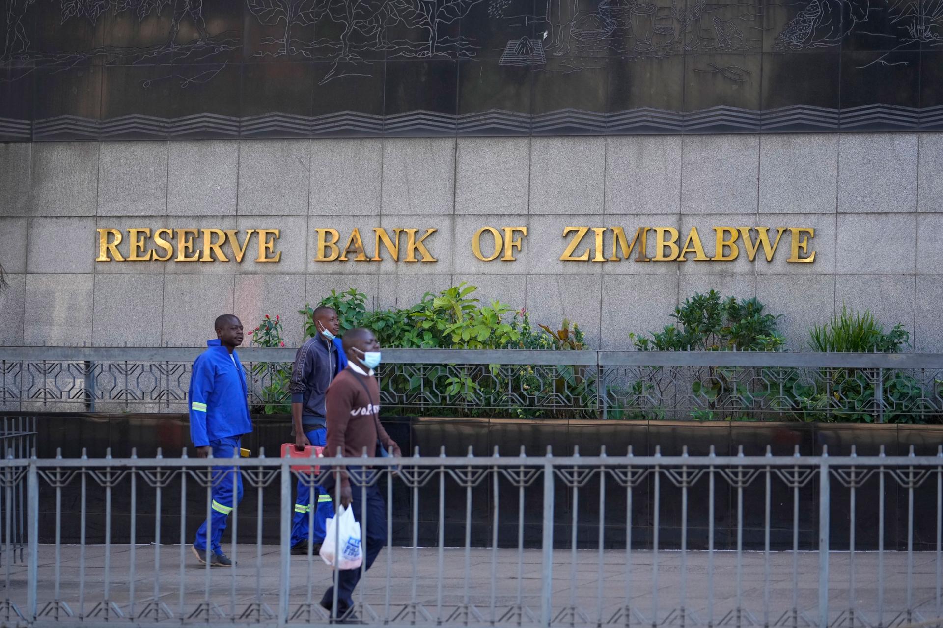 People walk past the Reserve Bank of Zimbabwe building, in Harare, Monday, July 25, 2022. 