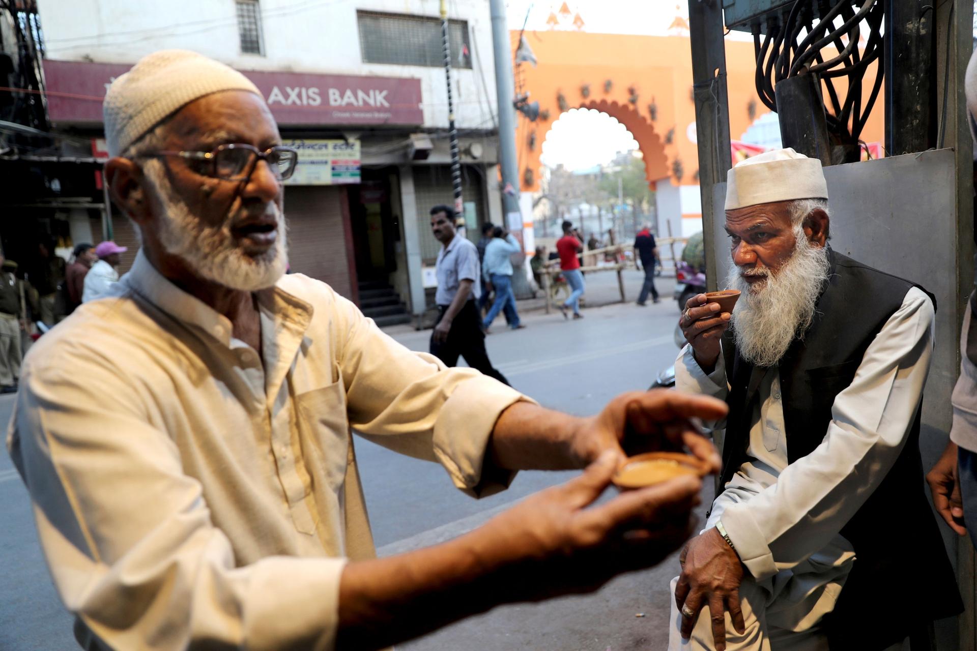 In this March 20, 2019, photo, Aijaz Mohammed Islahi, a caretaker of the 17th-century Gyanvapi mosque, right, sips tea outside the heavily guarded Vishwanath temple and mosque complex.