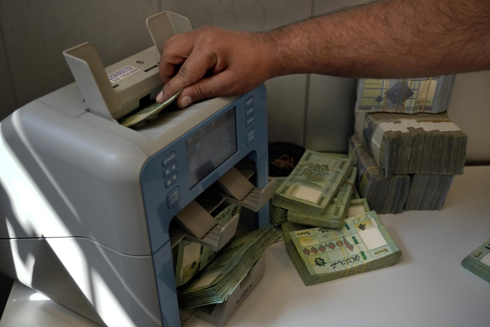 A worker at a money exchange bureau counts Lebanese pounds in Beirut, Lebanon