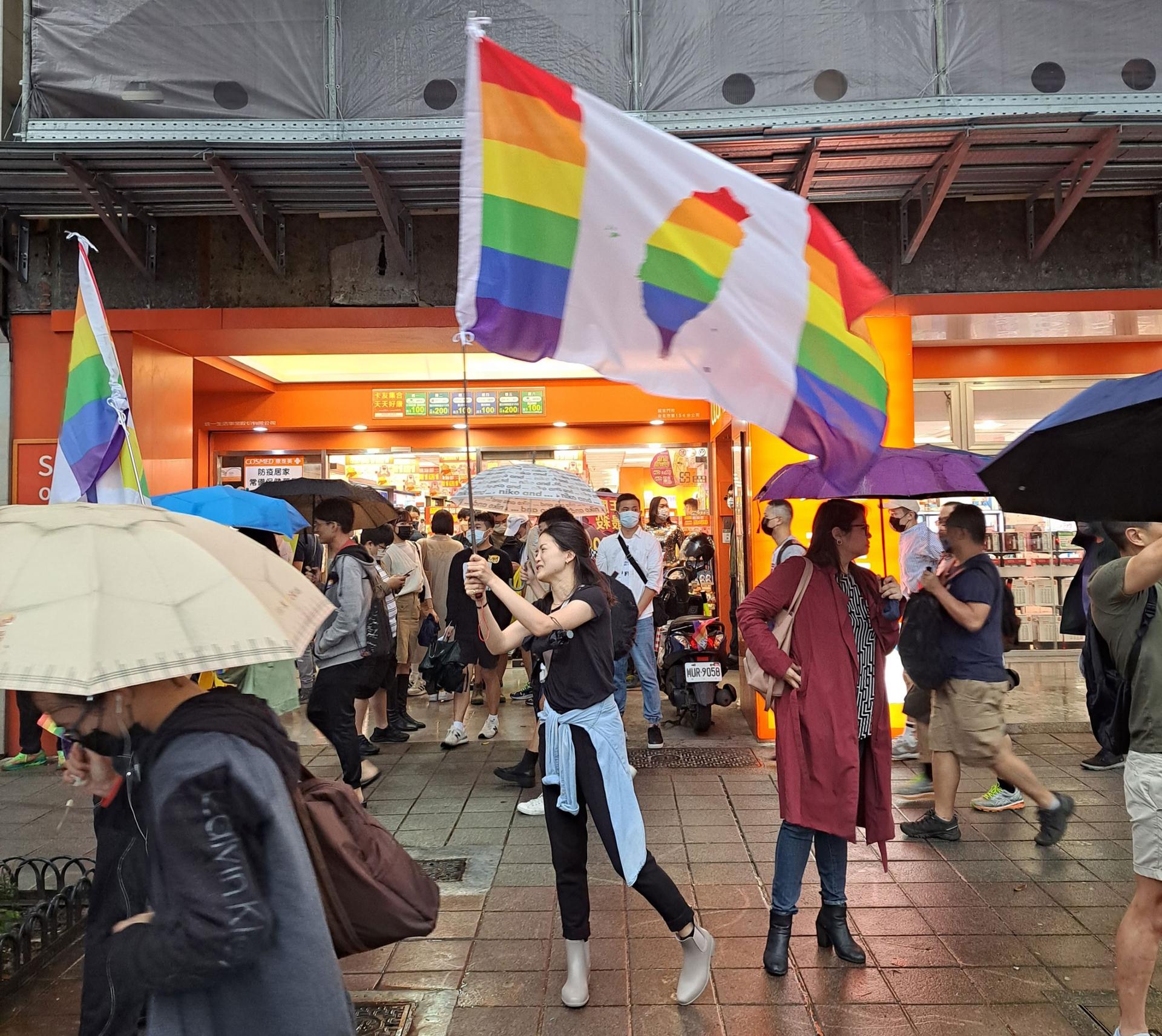 Attendees raise flags that combine symbols of Taiwanese sovereignty with rainbow Pride colors, at Taiwan's Pride celebration on Saturday, Oct. 29.