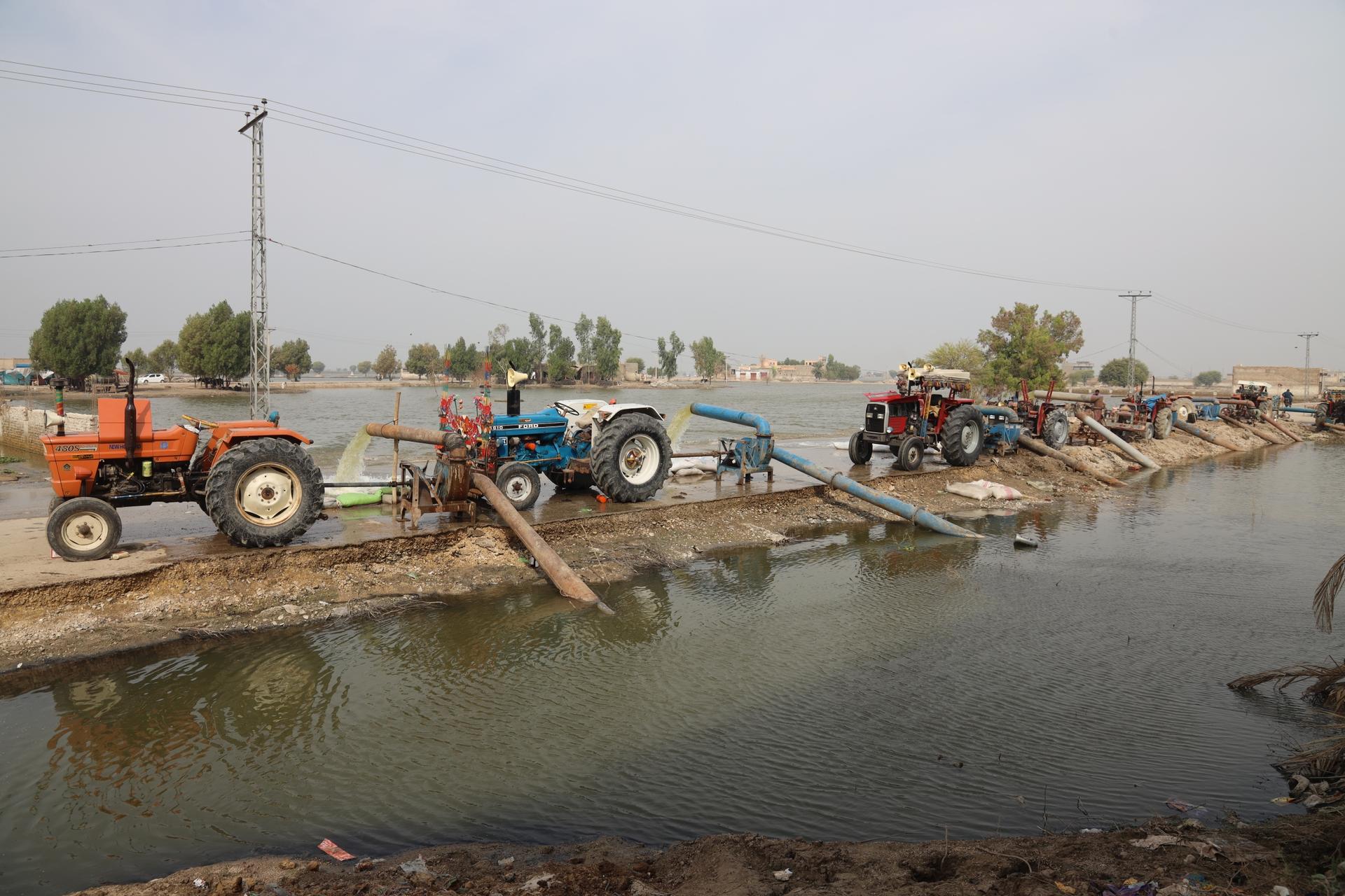 Pumps powered by tractor engines work to “de-water” flooded towns in Pakistan.