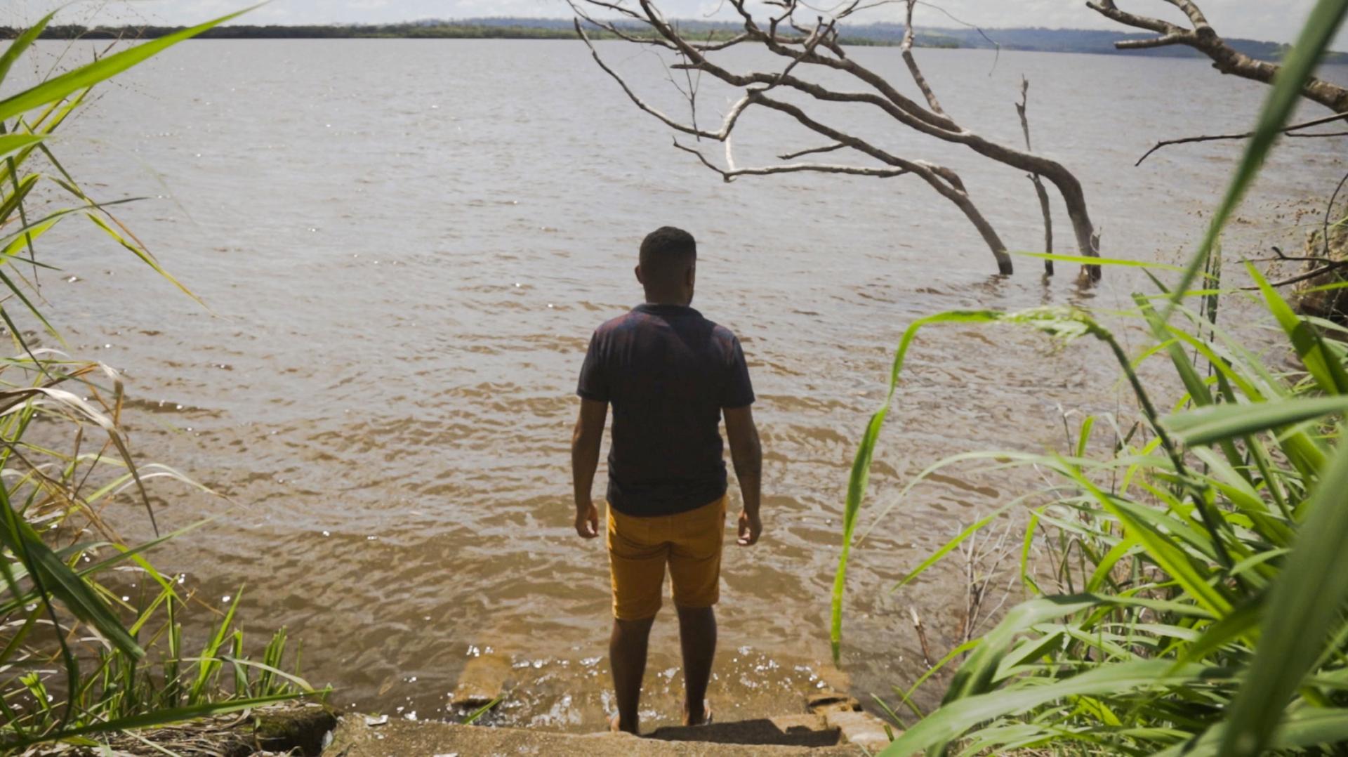 Cleyson Juruna stands at the edge of the Xingu river.