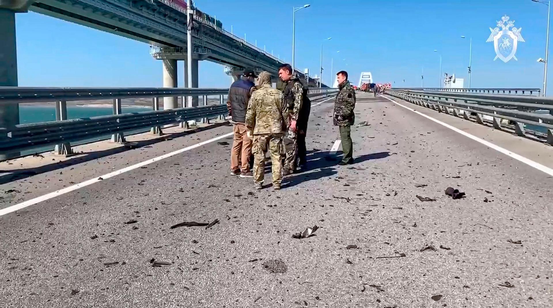 In this image taken from video released by the Russian Investigative Committee, employees of the Russian Investigative Committee work at the scene of a damaged part on Crimean Bridge connecting Russian mainland and Crimean peninsula over the Kerch Strait.