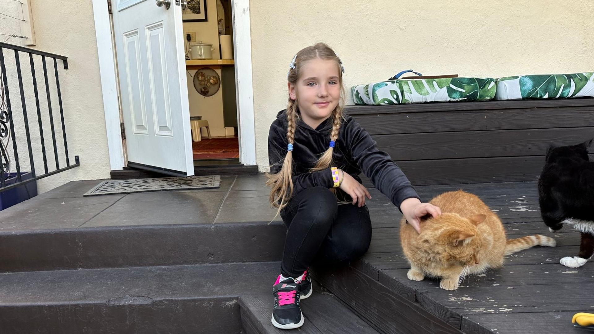 Vira Ustyanska's daughter Vasy plays with a cat in what is now her home in San Diego, California. Mother and daughter fled their town of Zaporizhzhia in the first weeks of the war in Ukraine.