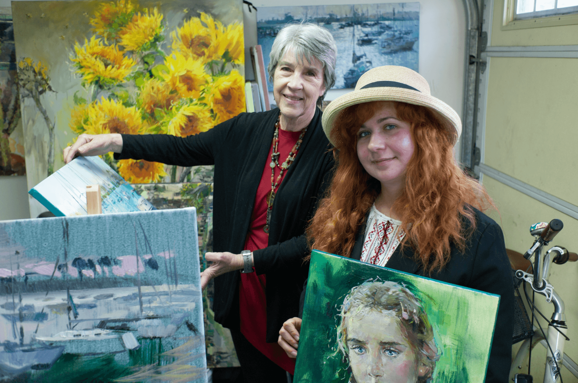 Ukrainian artist Vira Ustyanska with her host Connie Terwilliger in San Diego. At the garage-turned-art studio at Terwilliger's house, Ustyanska paints large canvases of sunflowers, her favorite subject.