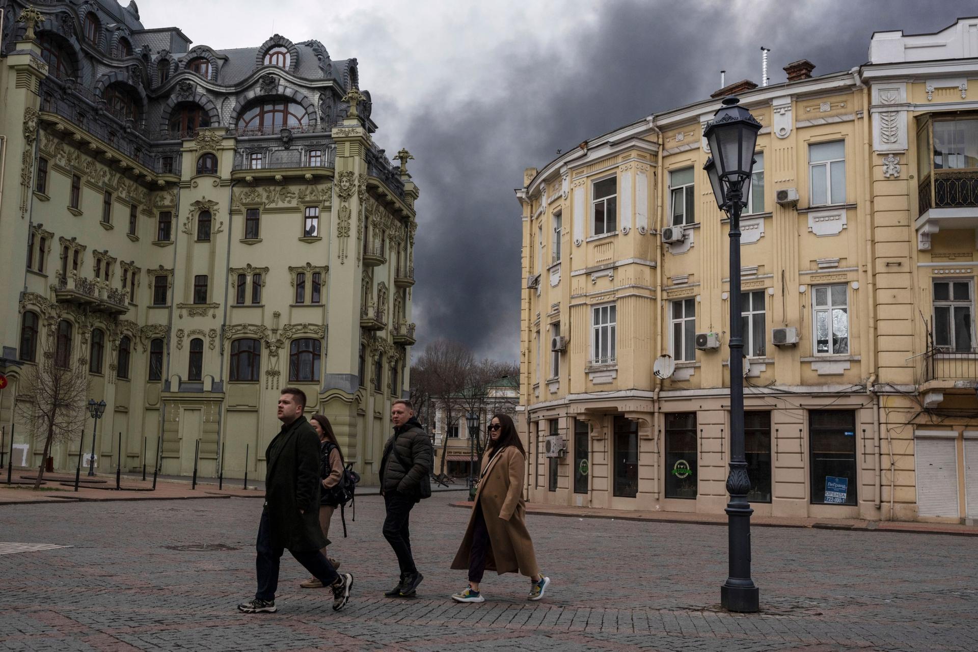 People walk in a street as smoke rises in the air after shelling in Odesa, Ukraine, Sunday, April 3, 2022.