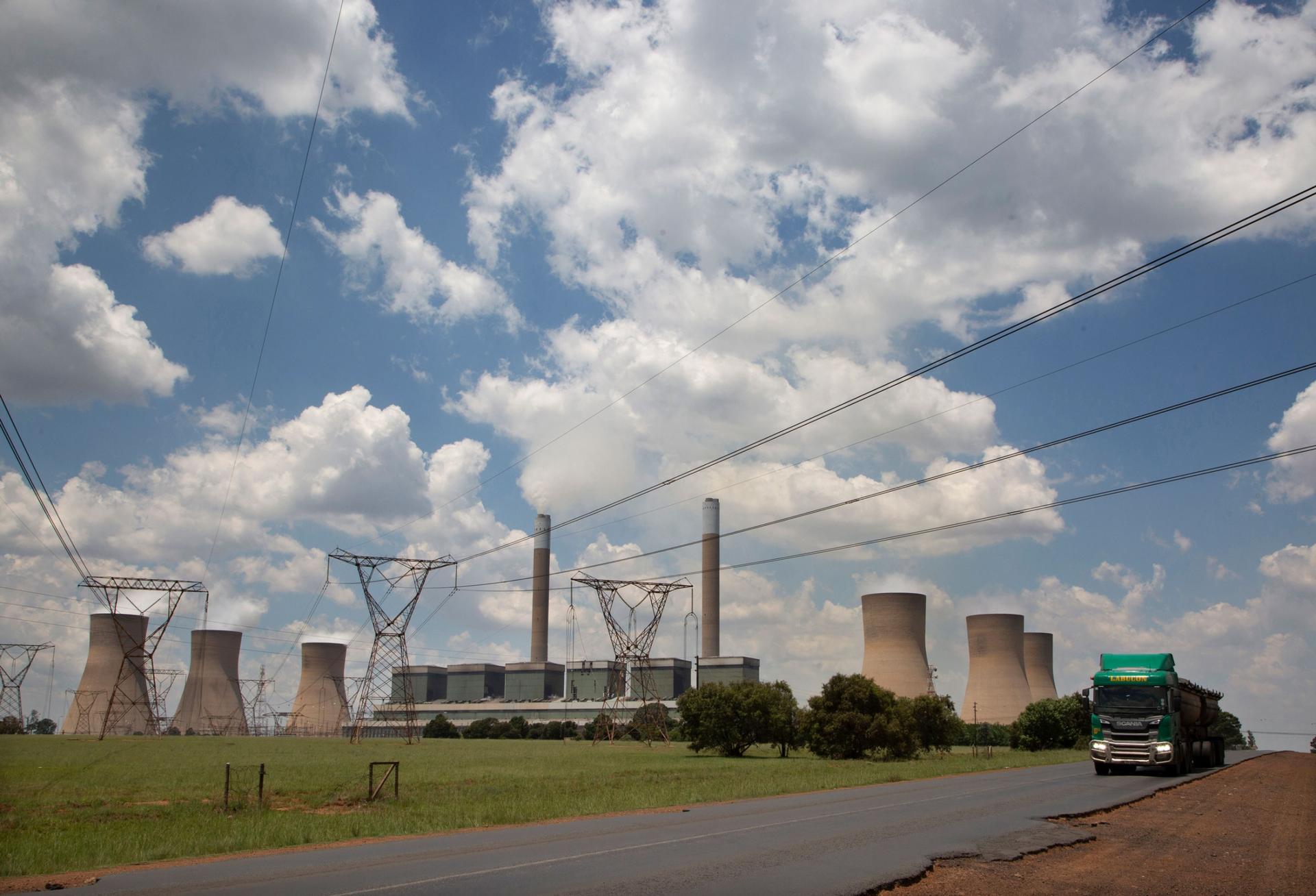 A coal truck, right, passes the coal-powered Duvha power station, near Emalahleni (formerly Witbank) east of Johannesburg, Thursday, Nov. 17, 2022. 