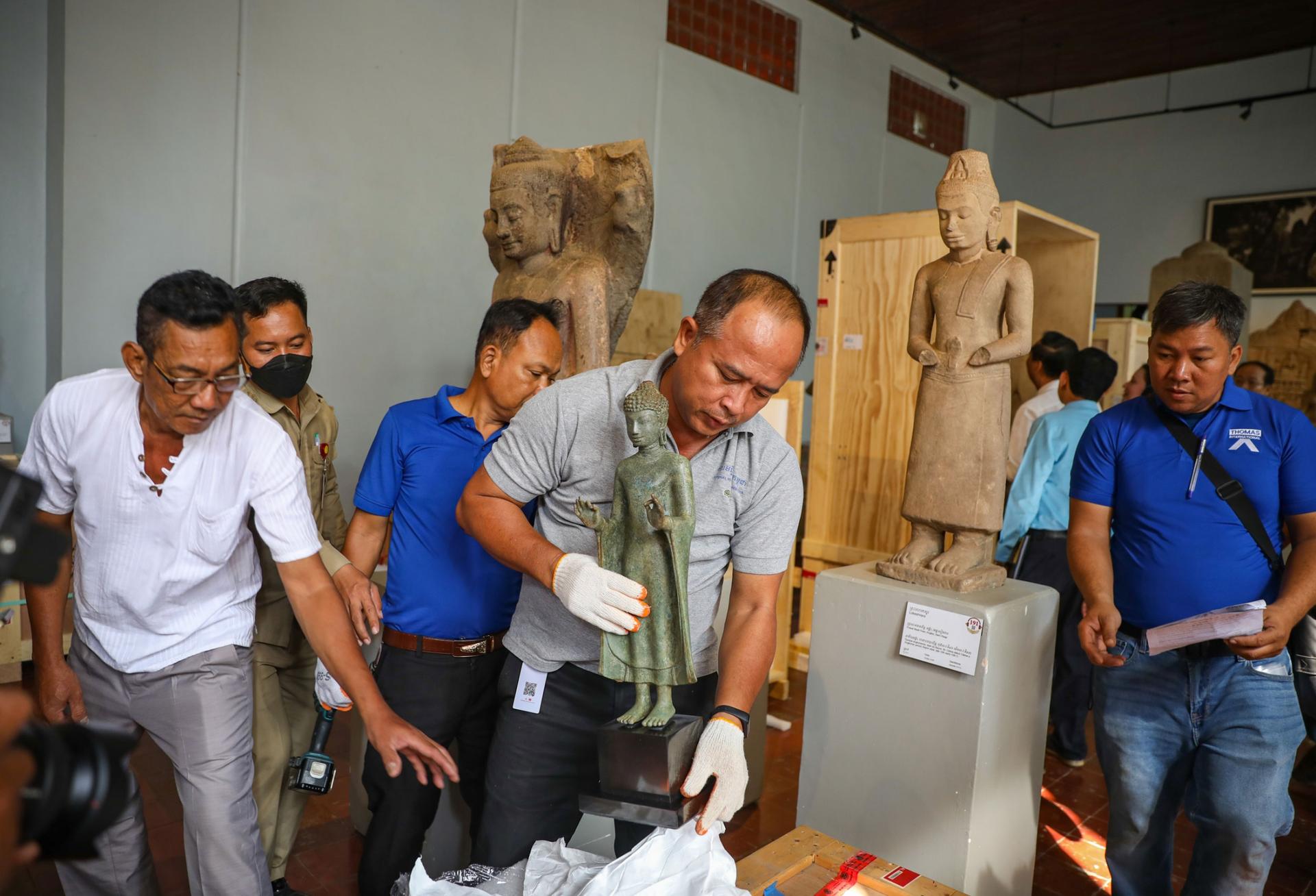 Sok Soda, deputy director of the National Museum of Cambodia in Phnom Penh, unpacks a bronze standing Buddha statue.