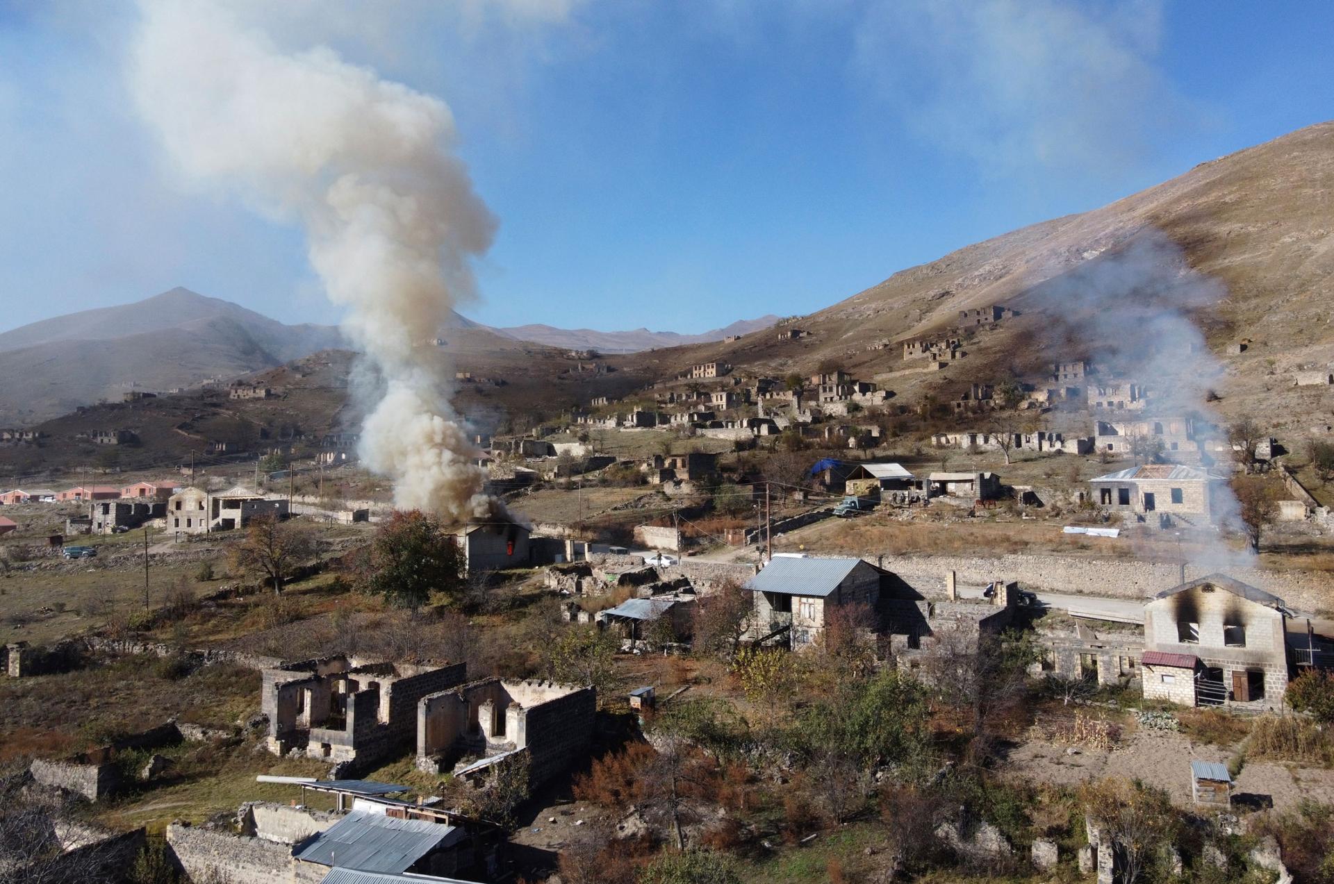 In this photo taken with a drone, smoke rises from burning houses as people leave the separatist region of Nagorno-Karabakh to Armenia, Saturday, Nov. 14, 2020. 