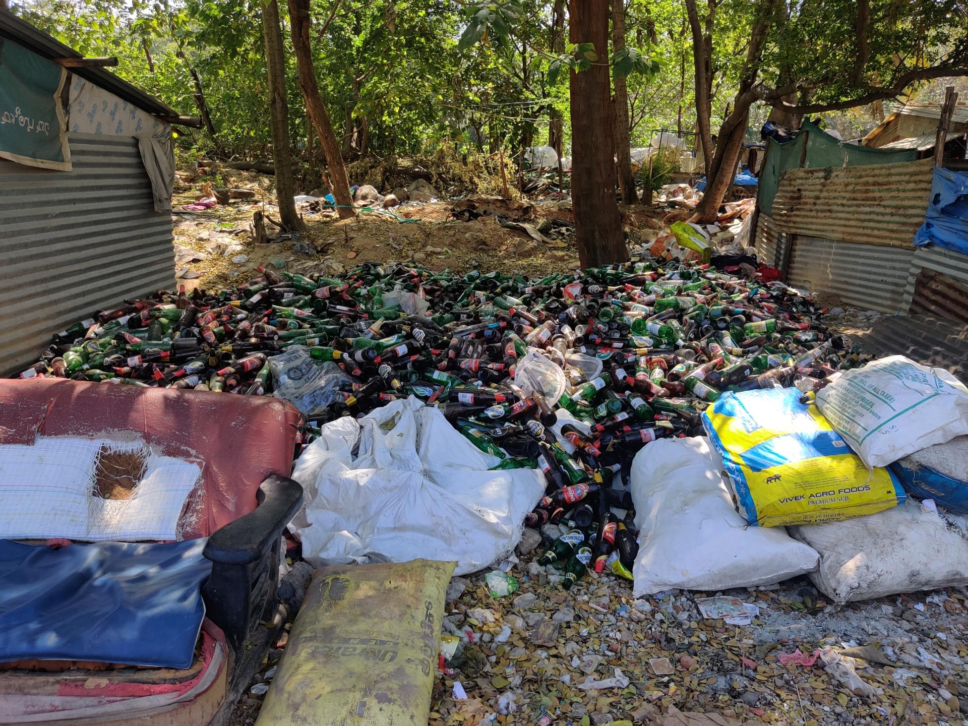 Trash segregators in Bangalore, India, pile up glass bottles to one side as they separate waste.