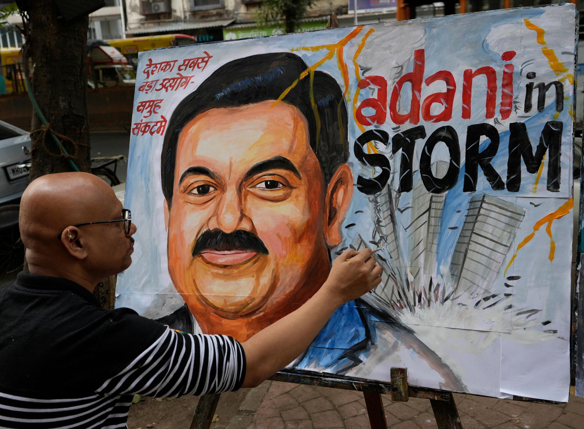 Sagar Kambli, an artist and a school teacher, gives final touches to a painting of Indian businessman Gautam Adani, depicting the ongoing crisis of the Adani group, in Mumbai, India, Friday, Feb. 3, 2023. 