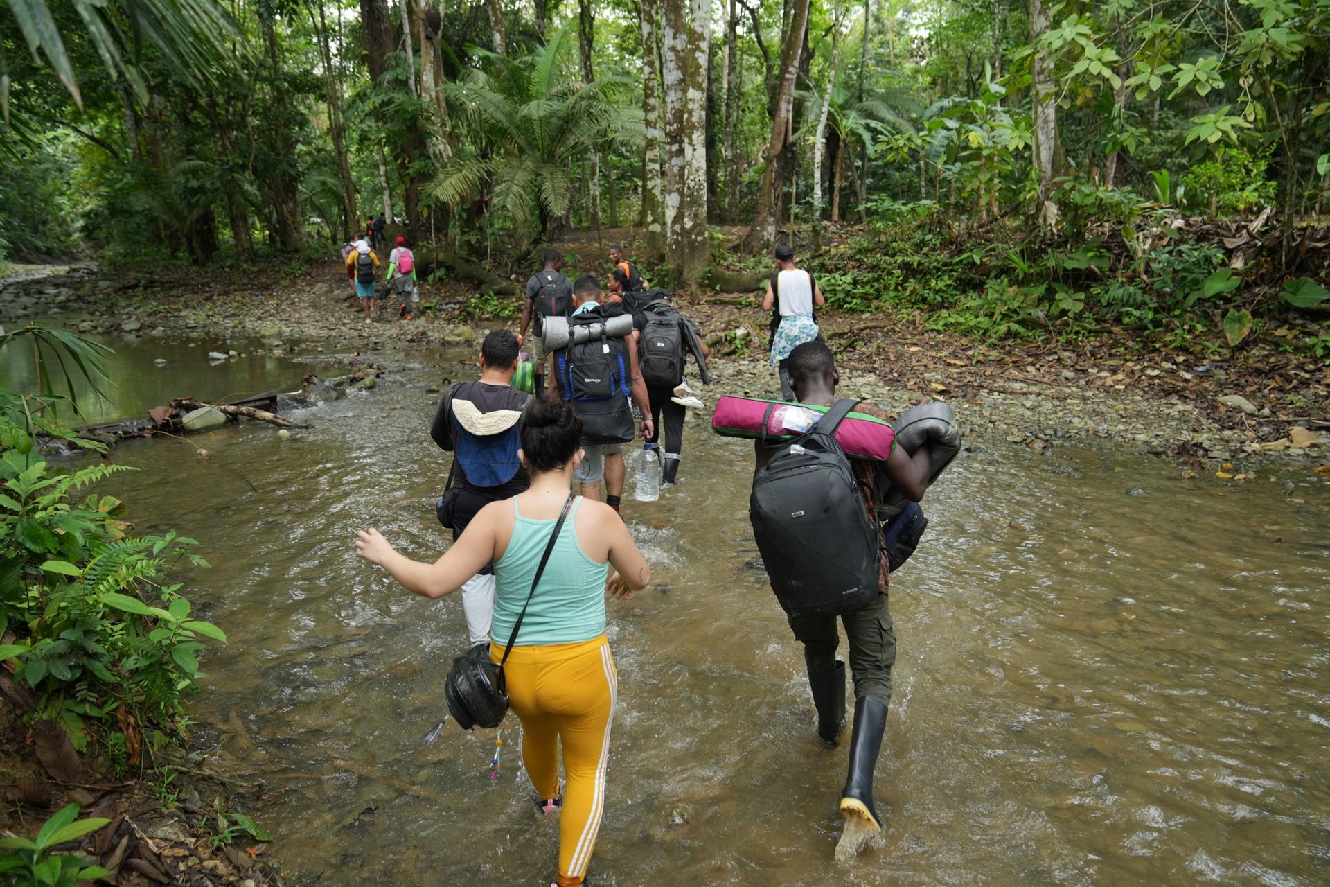 A group of migrants from Venezuela, Haiti and Burkina Faso crosses a stream in the rainforest as they being the three day trek across the Darien jungle. 