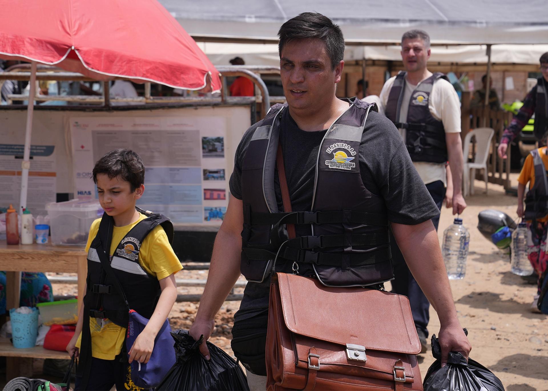 Abdul Bais, a former diplomat for Afghanistan, leads a group of migrant families. As he gets ready to board a speedboat in Necocli, Colombia, he carries his documents in a leather briefcase.