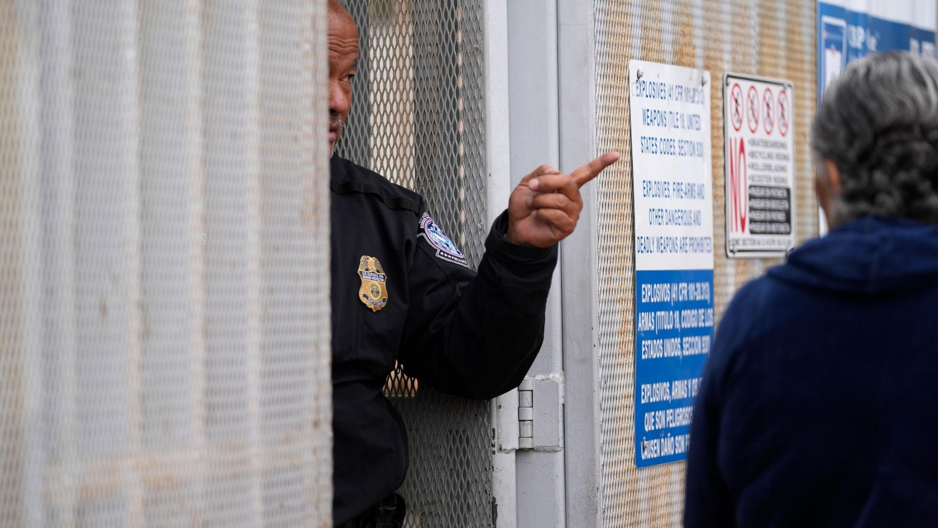 A United States Customs and Border Protection officer points toward a line of people at the entrance to the San Isidro Port of Entry, linking Tijuana, Mexico with San Diego, Thursday, June 1, 2023, in Tijuana, Mexico.