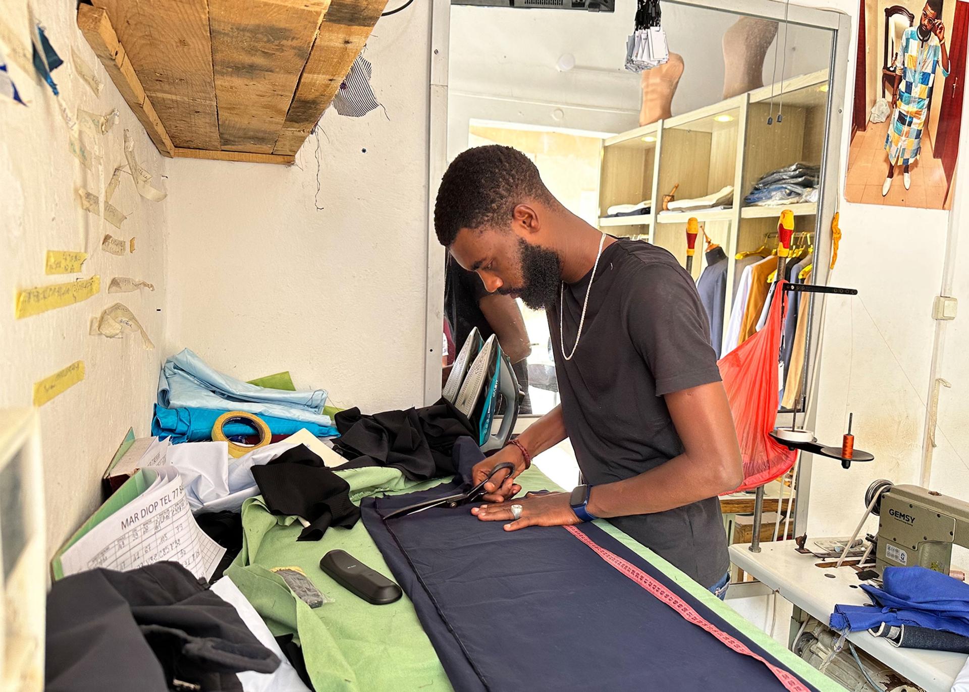 Mar Diop cuts fabric at this tailor shop in St. Louis, Senegal. He is working long hours to fill custom-made orders for Eid.