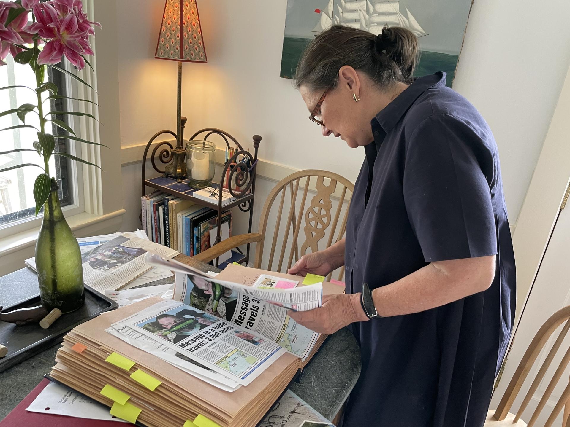 Sharon Ames looks through scrapbooks of responses from people who found bottles with notes tossed into the ocean by her husband, Pennel Ames, in their home in Nantucket, Massachusetts, Jul. 30, 2023.