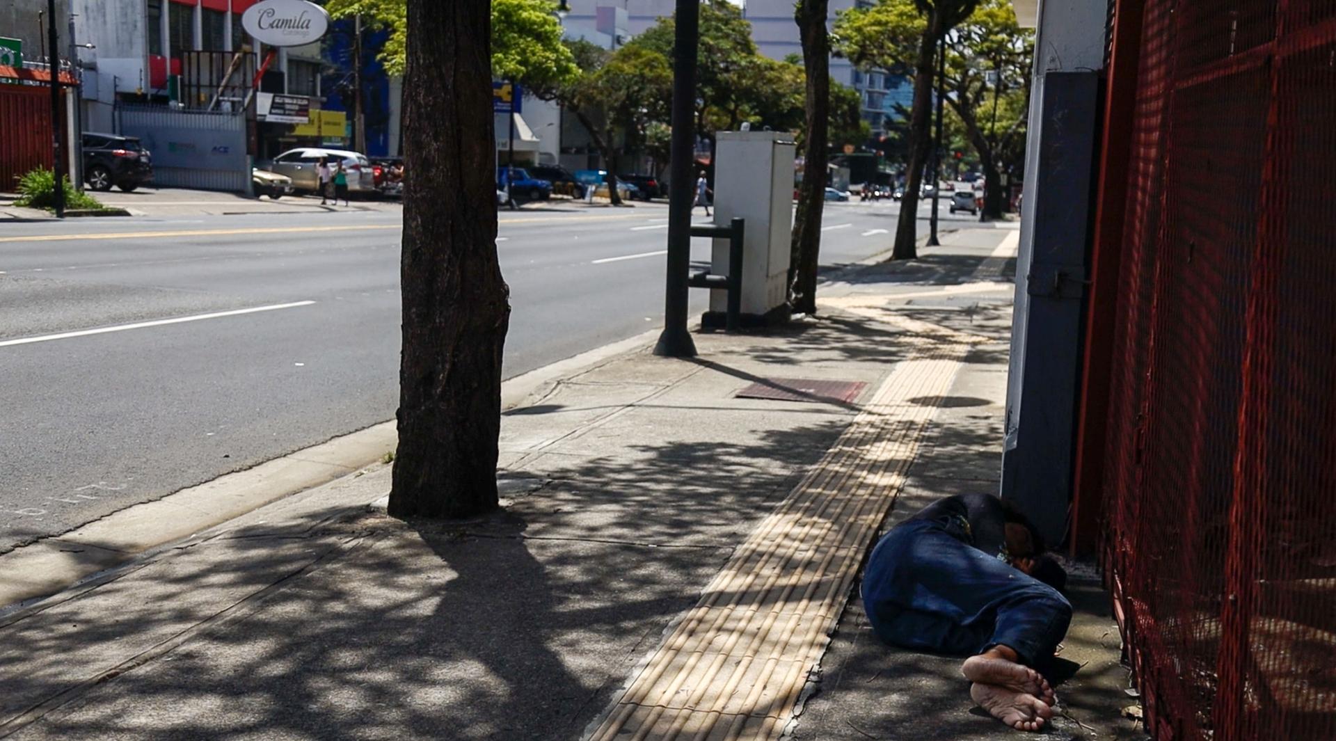 A man is lying in the streets of downtown San Jose, Costa Rica. 