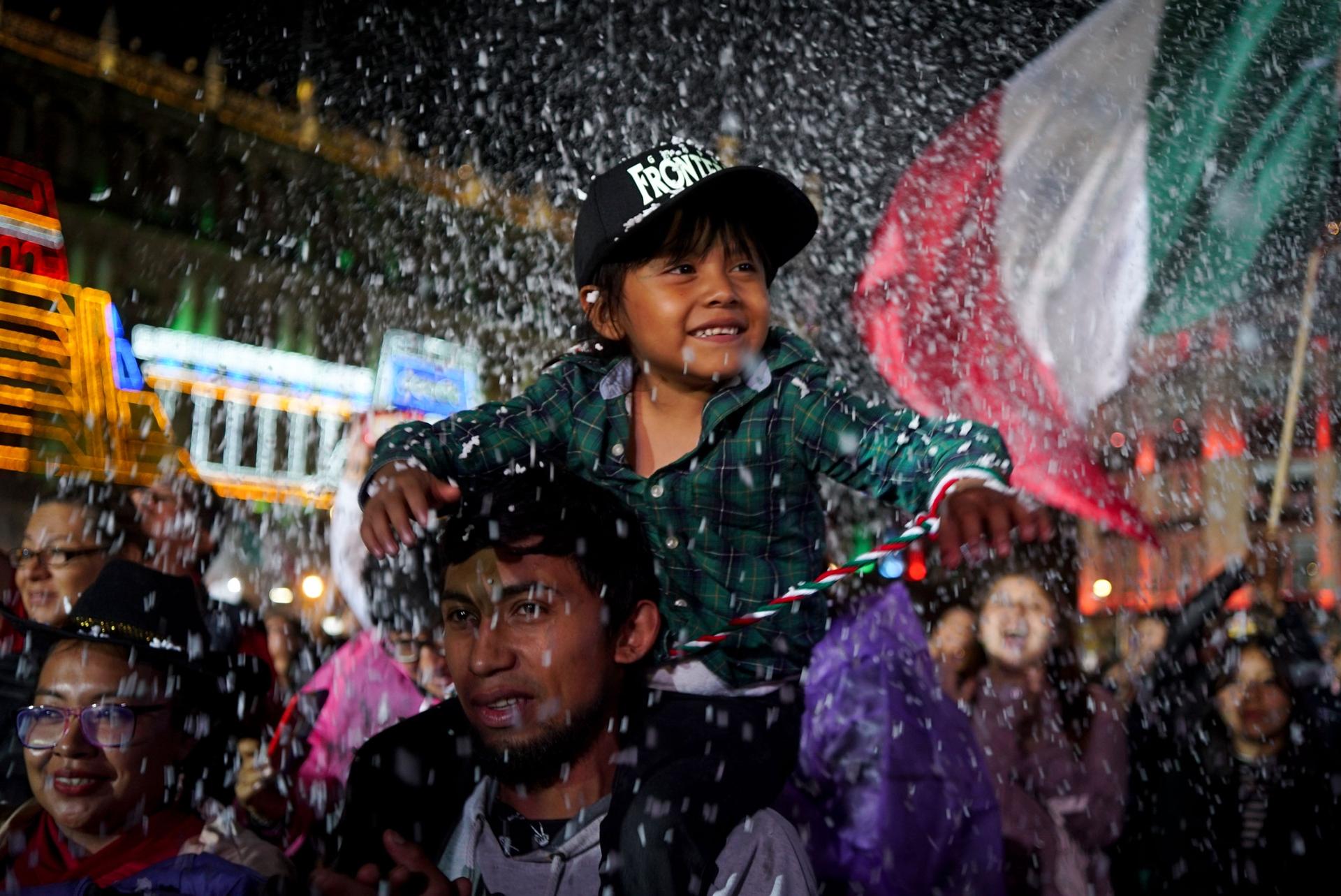 A boy sits on his father's shoulders during the Sept. 15 concert to celebrate Mexican Independence Day, Mexico City, Mexico. 
