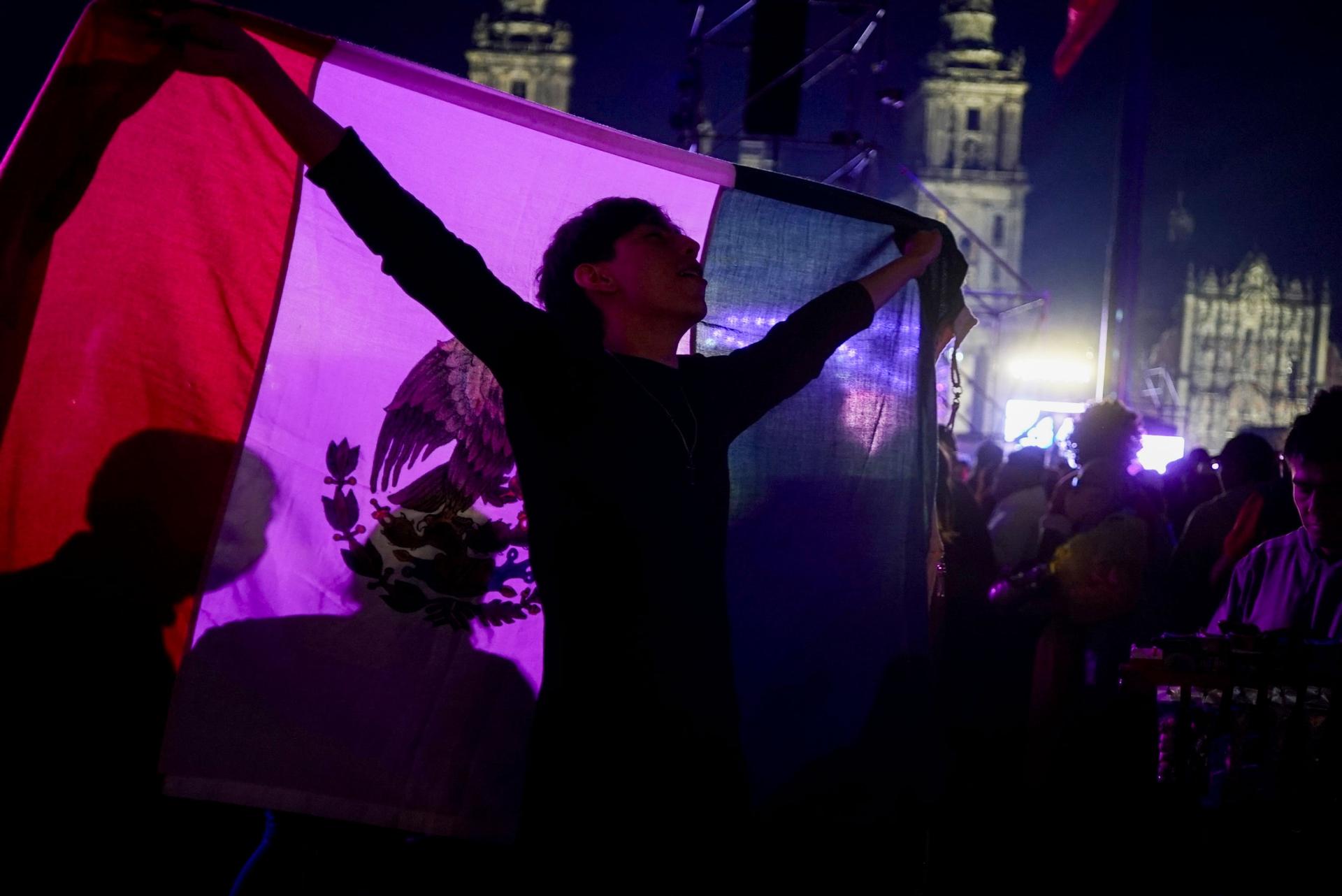 A concert-goer waves a Mexican flag behind him while celebrating Mexican independence, Sept. 15, 2023, Mexico City.
