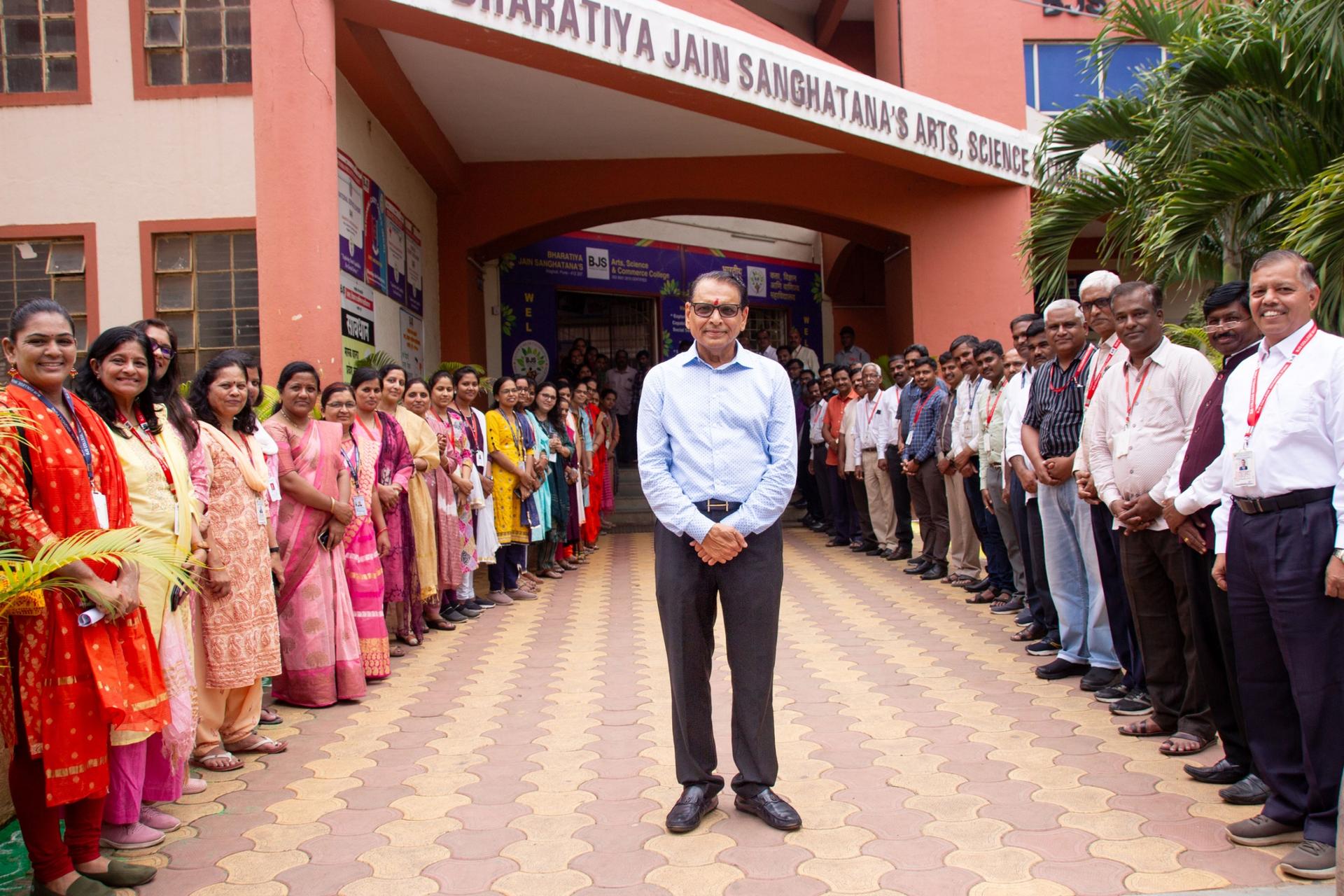 Shantilal Muttha, founder of Bharatiya Jain Sanghatana, stands in front of the school with teachers and staff. 