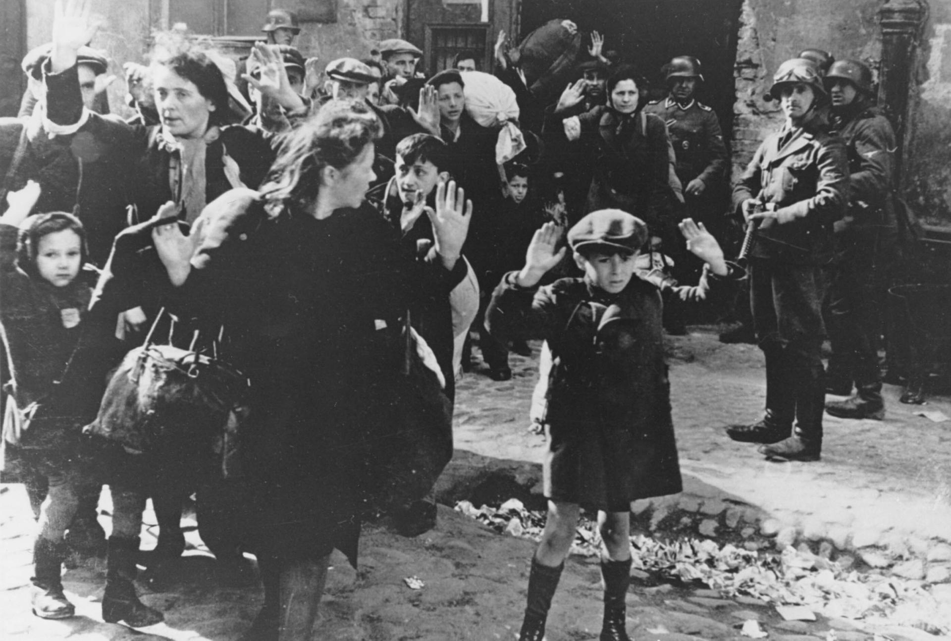 A group of Jewish people is escorted from the Warsaw Ghetto by German soldiers on April 19, 1943.