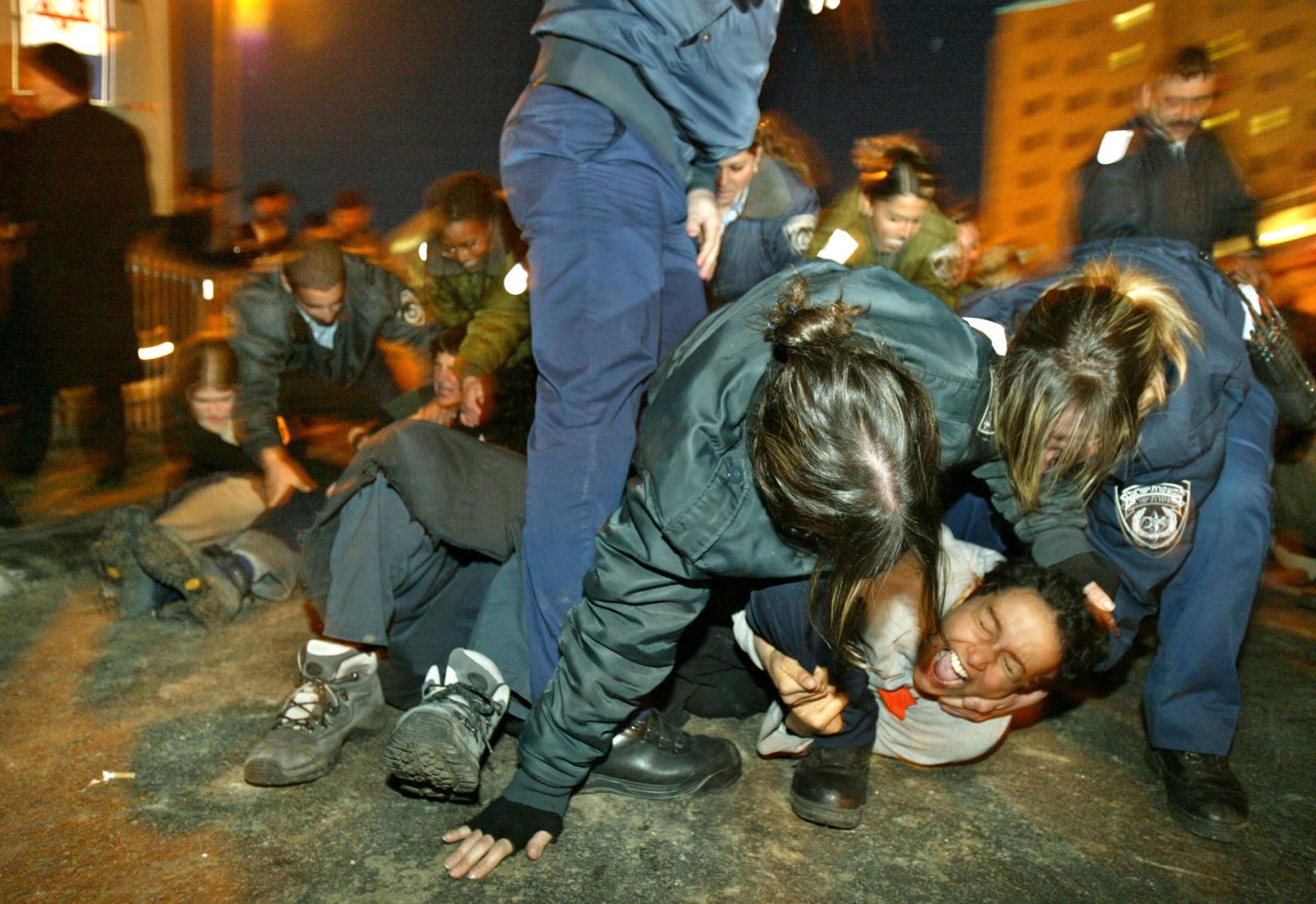 Israeli police women scuffle with a female Israeli demonstrator during a rally against PM Ariel Sharon's disengagement plan, in Jerusalem, Feb. 14, 2005.