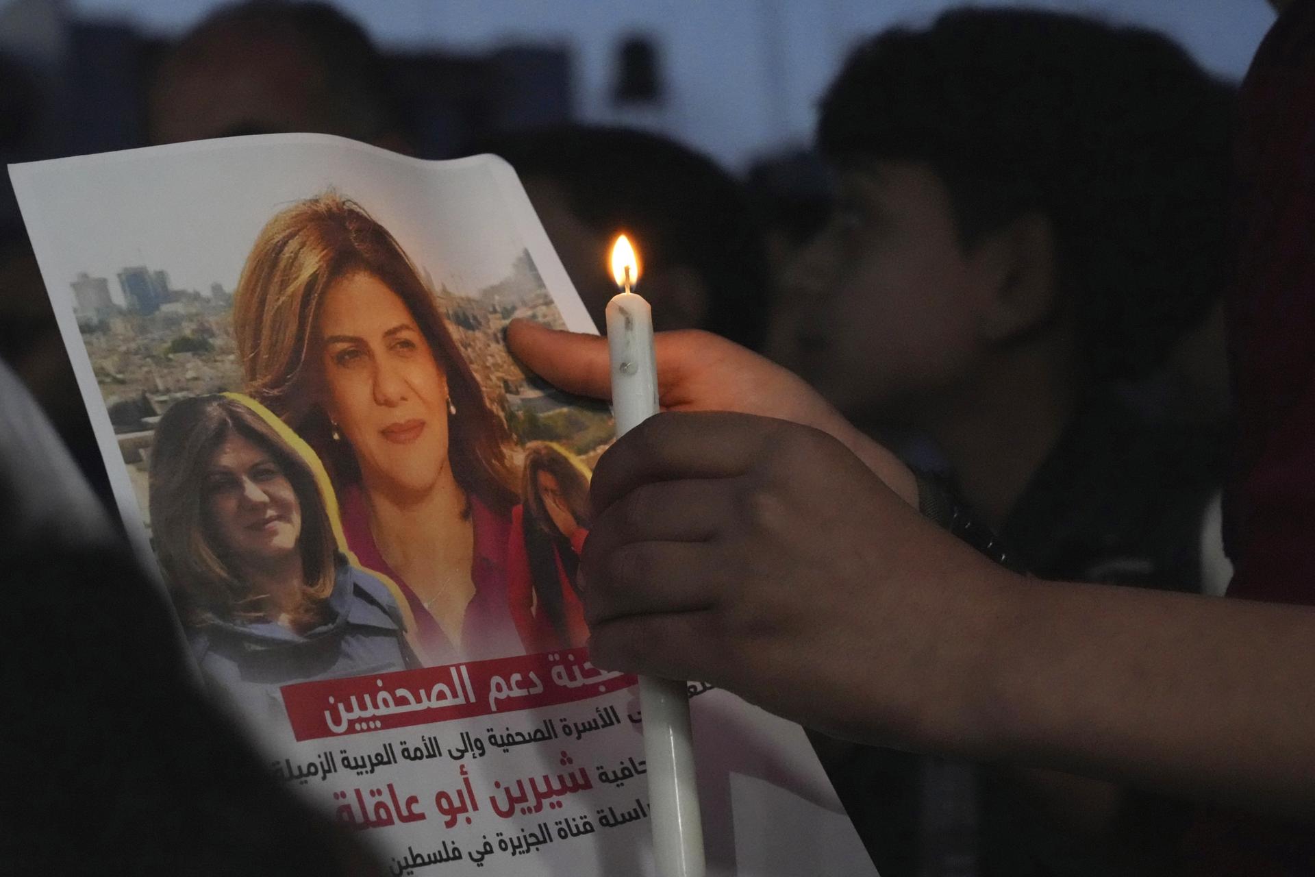 A Palestinian holds a light candle and a picture of slain Al Jazeera journalist Shireen Abu Akleh, to condemn her killing, in front of the office of Al Jazeera network, in Gaza City, May 11, 2022.