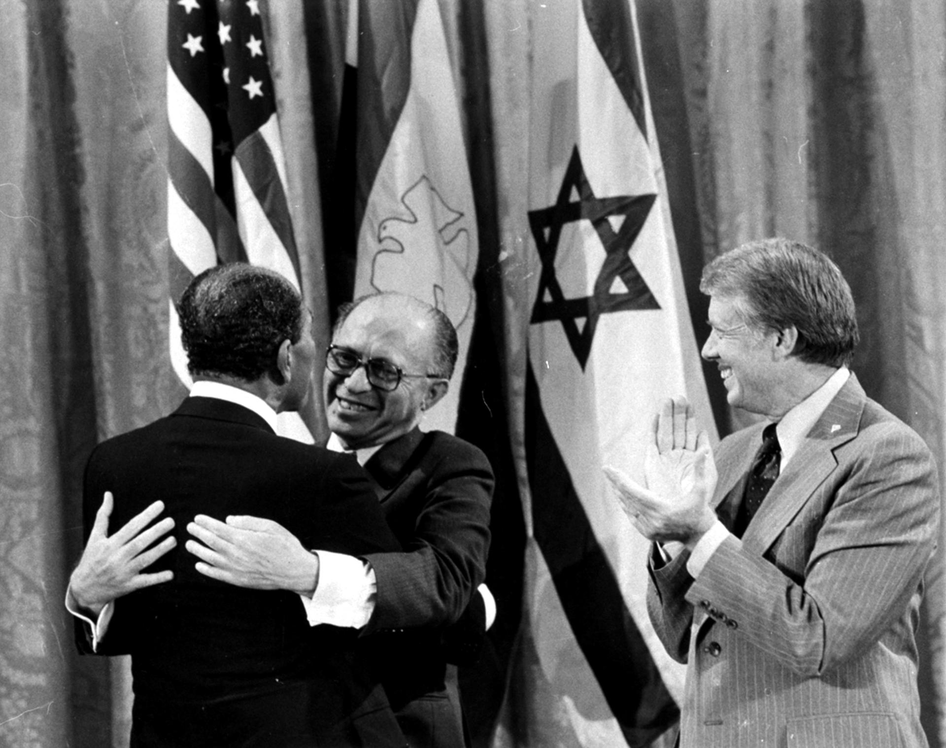 Egyptian President Anwar Sadat, left, and Israeli Prime Minister Menachem Begin, embrace as US President Jimmy Carter looks on after a peace deal at Camp David, Sept. 18, 1978.