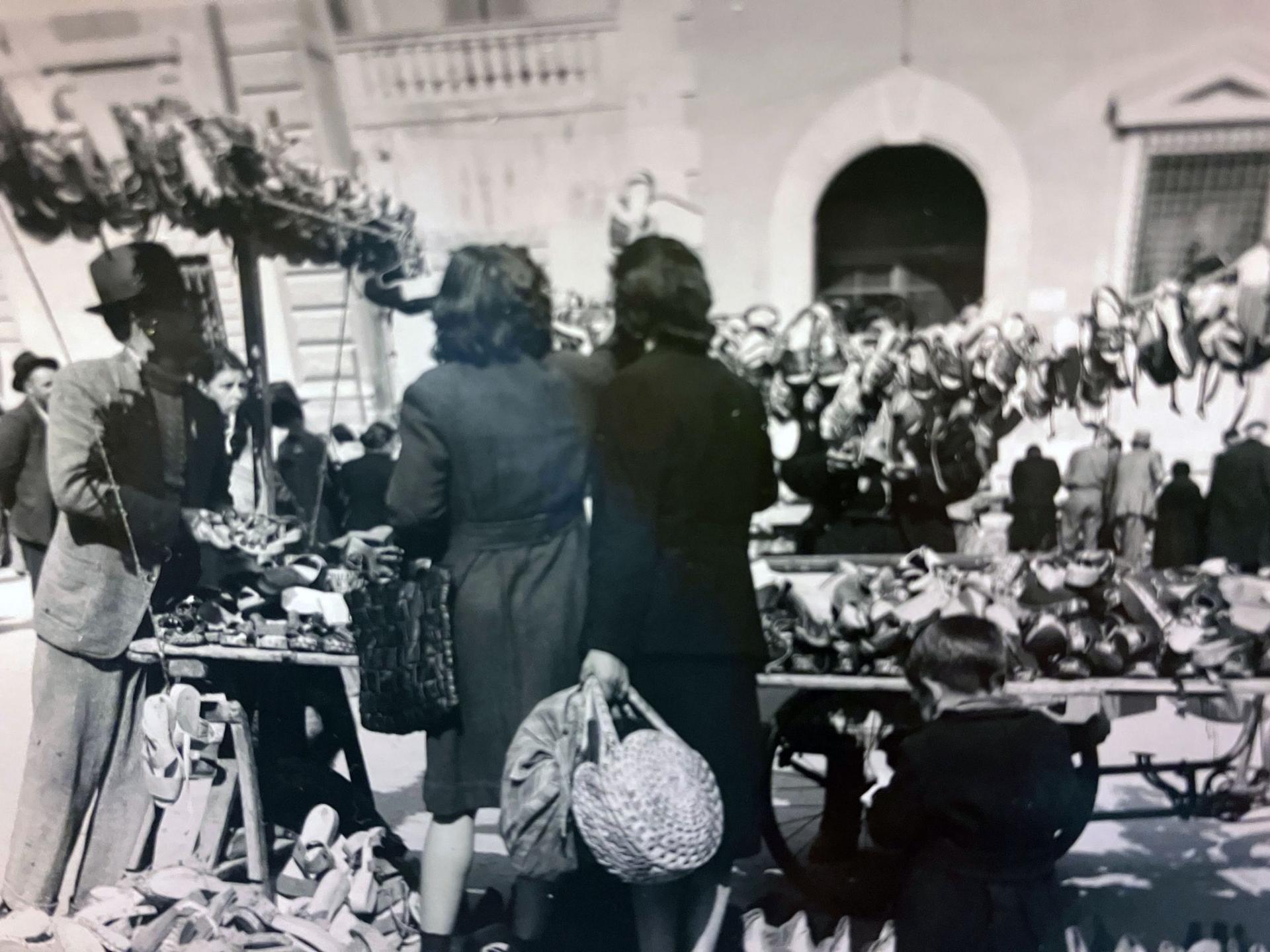 A bustling market scene with two women at a shoe stall in southern Italy, 1945. 