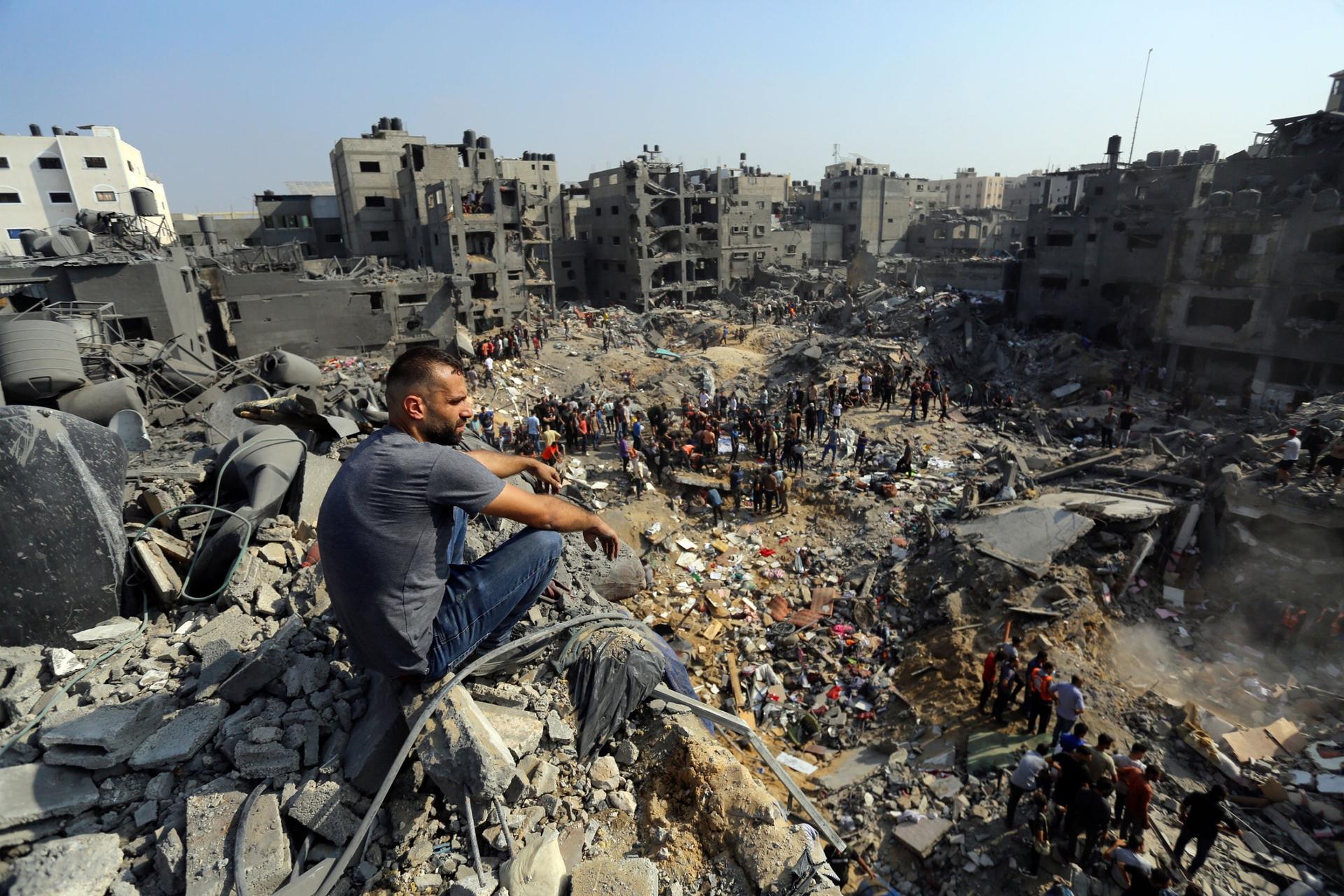 A man sits on the rubble as others wander among debris of buildings that were targeted by Israeli airstrikes in Jabaliya refugee camp, northern Gaza Strip, Wednesday, Nov. 1, 2023. 