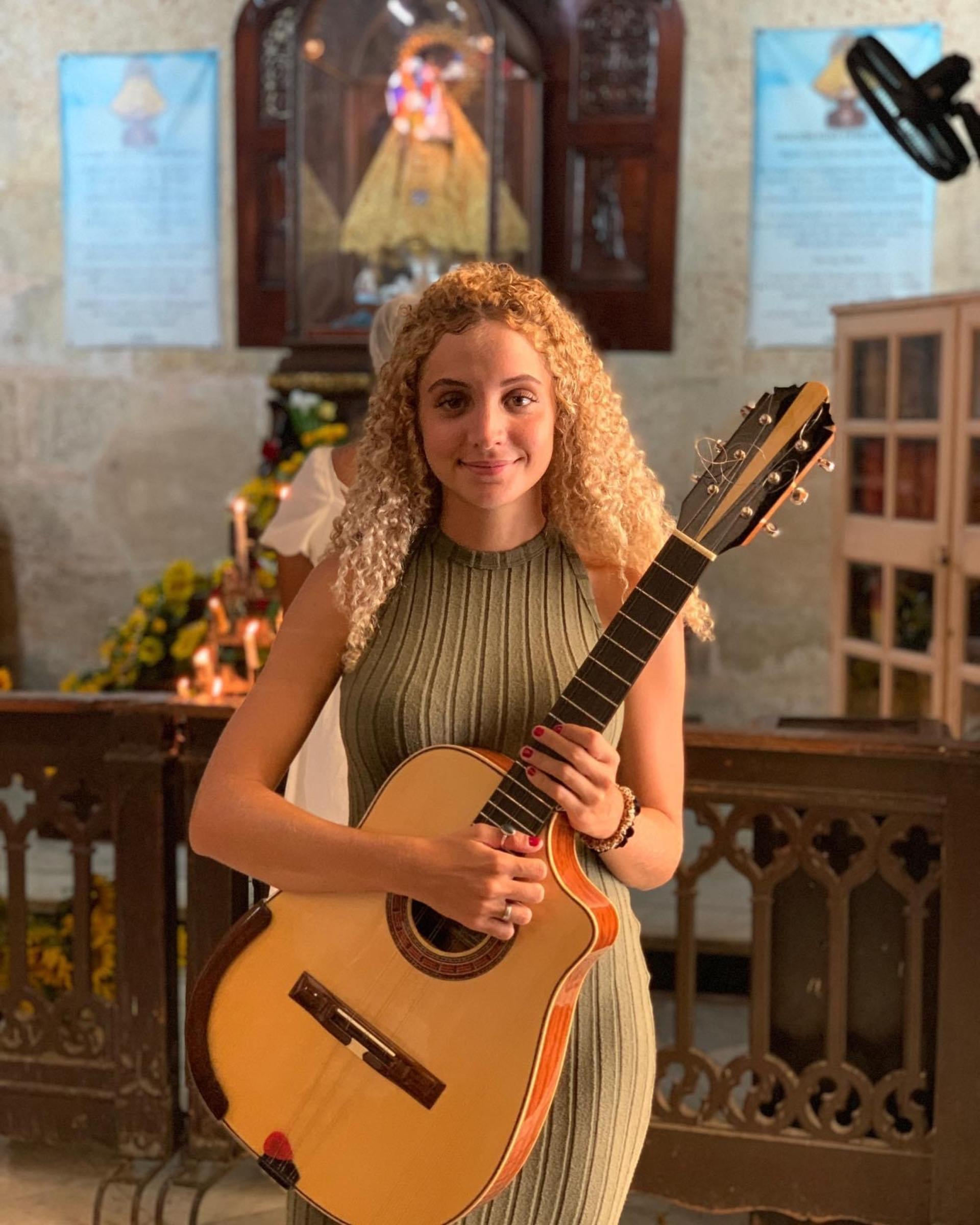 A young woman standing with the Cuban tres instrument