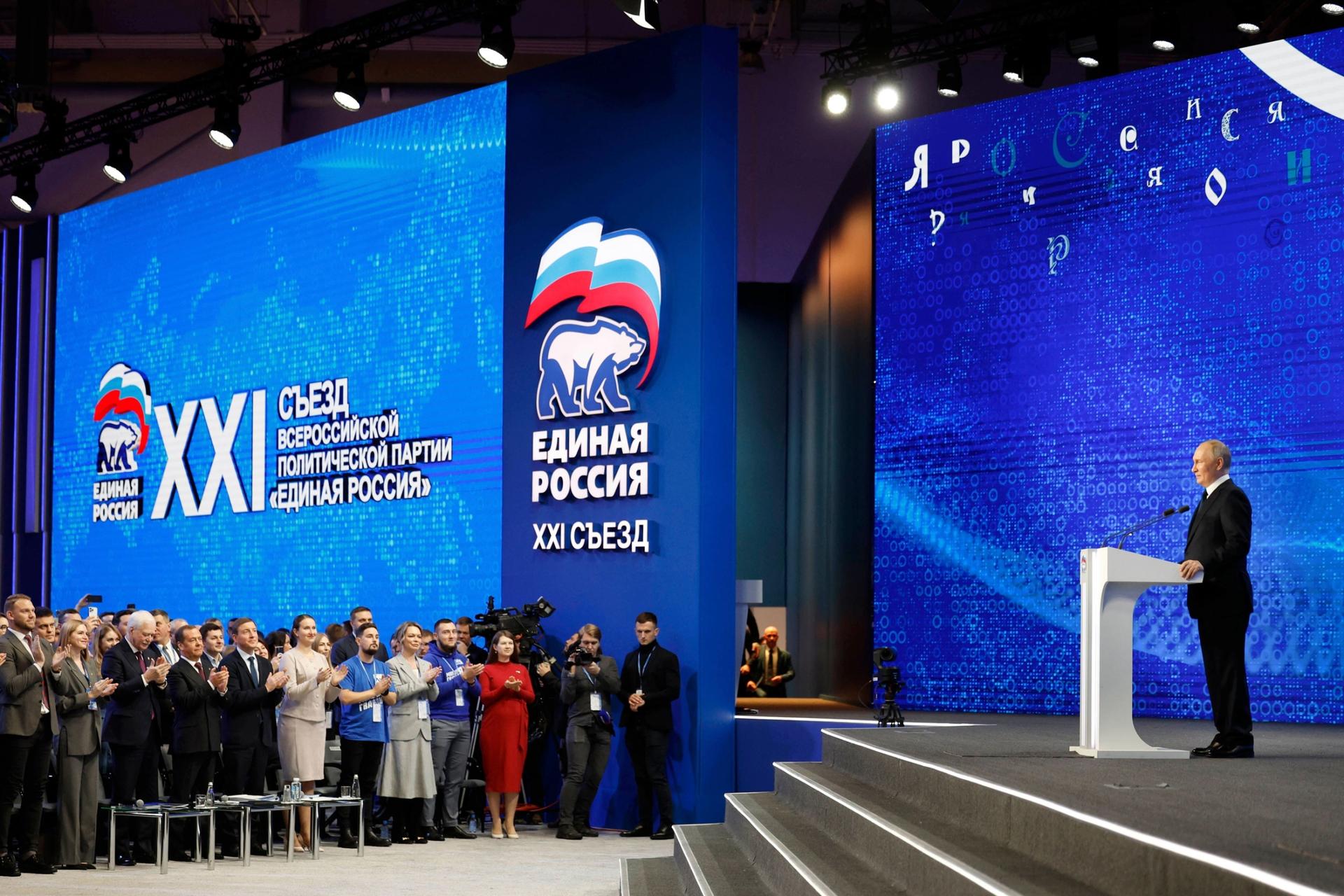 Participants applaud as Russian President Vladimir Putin, right, delivers his speech at the United Russia party congress in Moscow, Russia, Sunday, Dec. 17, 2023. 