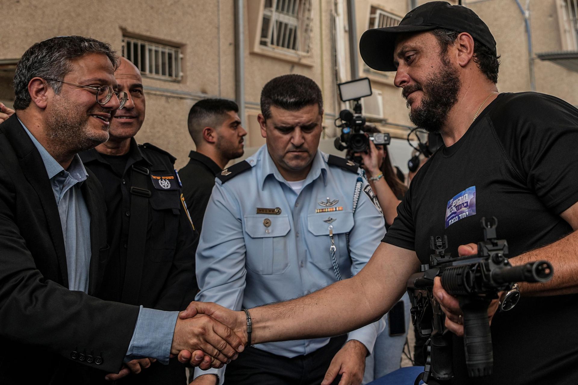 An Israeli volunteer of a local security group shakes hands with Israel's National Security Minister Itamar Ben-Gvir after receiving a weapon in Ashkelon, Israel, Friday, Oct. 27, 2023. 