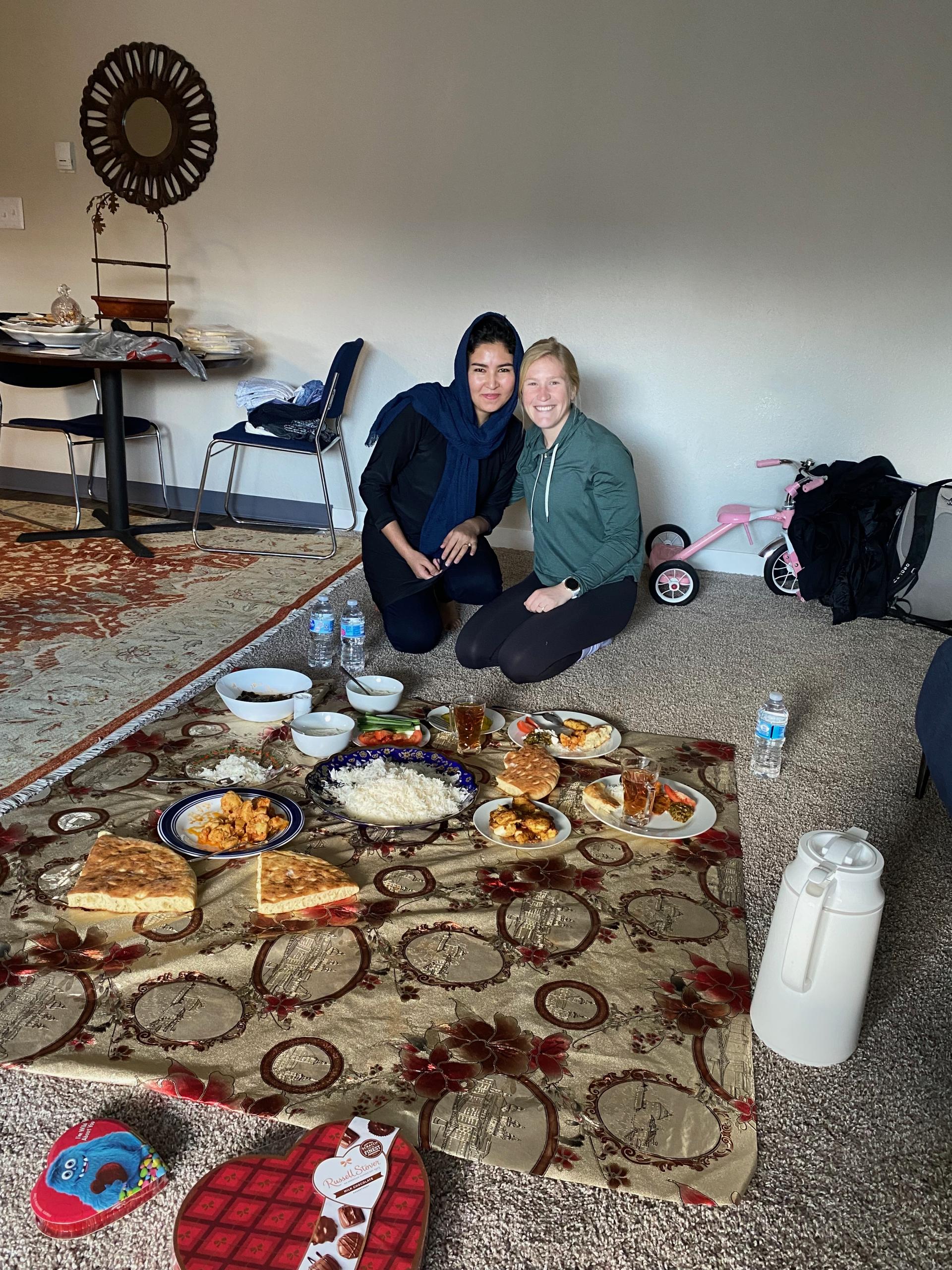 two women on a blanket with food