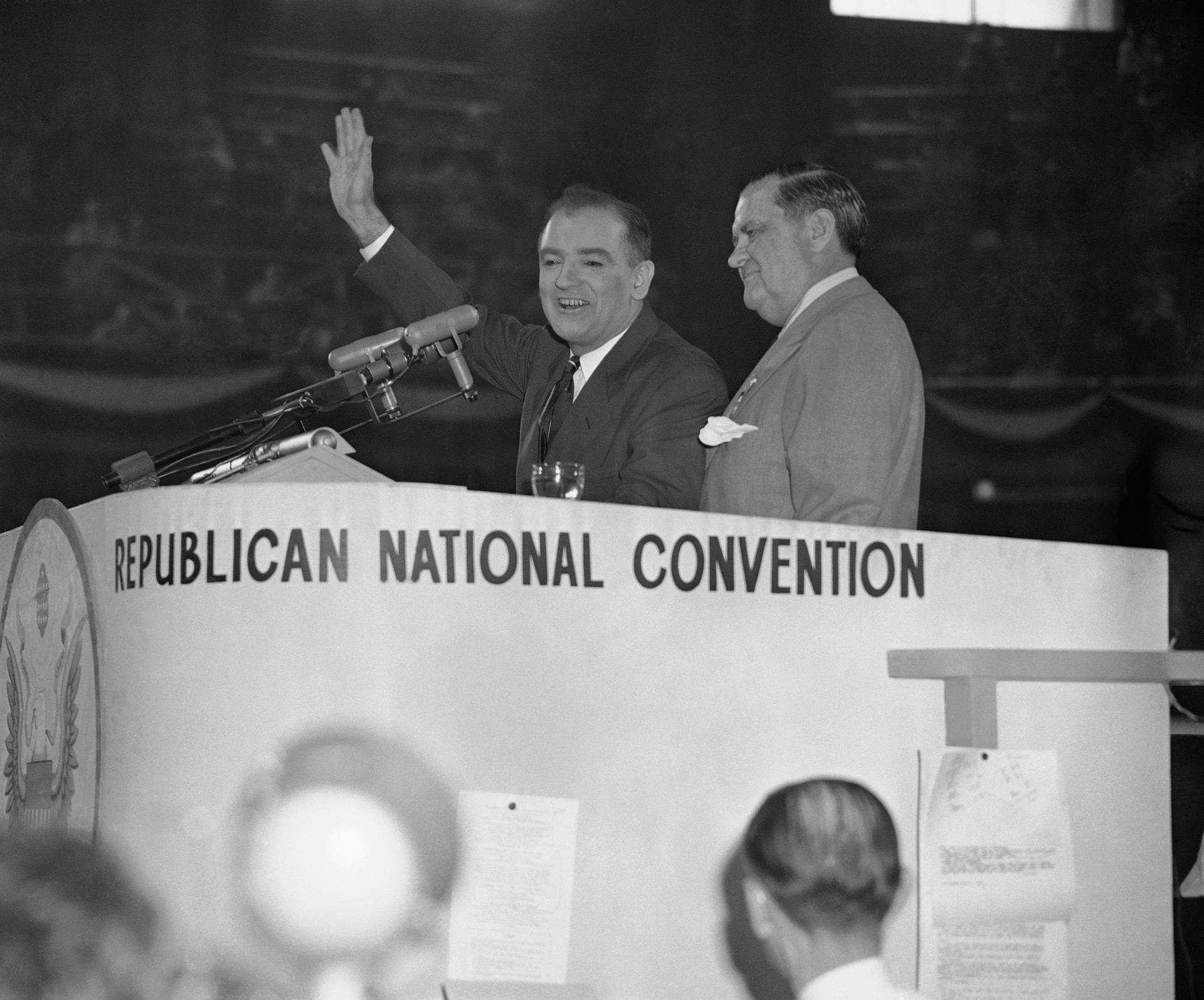 A black and gray photo of Sen. Joseph McCarthy and another male, both in suits, standing behind a podium that says Republican National Convention