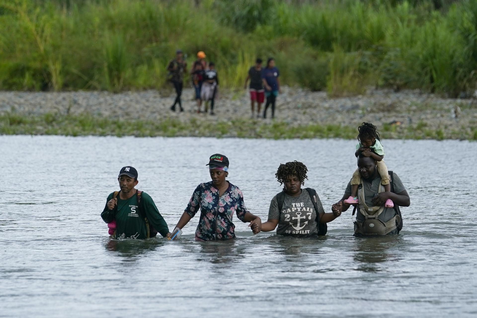 Haitian migrants wade across the Tuquesa river, Panama, Oct. 4, 2023. Dozens of charter flights believed to be carrying migrants fleeing Haiti have touched down in Nicaragua, the latest in a historic rush of migration to the US.