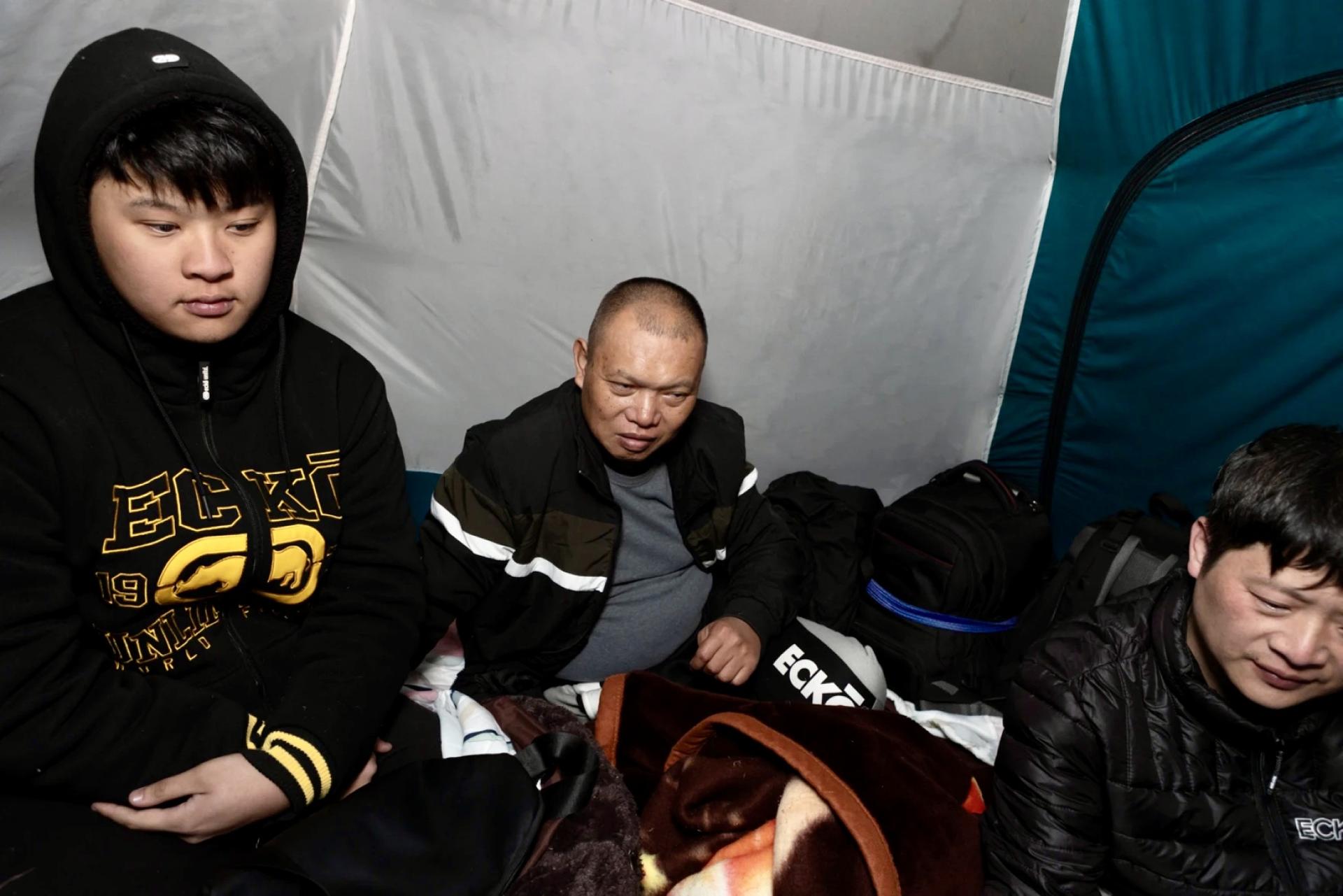 Three Chinese men wearing casual wear and sitting in a tent