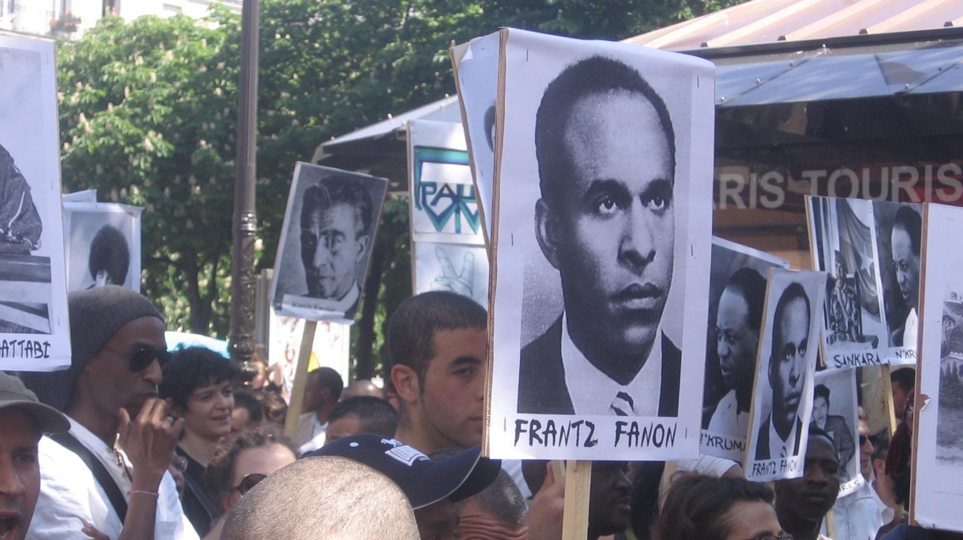 a sign of Frantz Fanon at a protest 