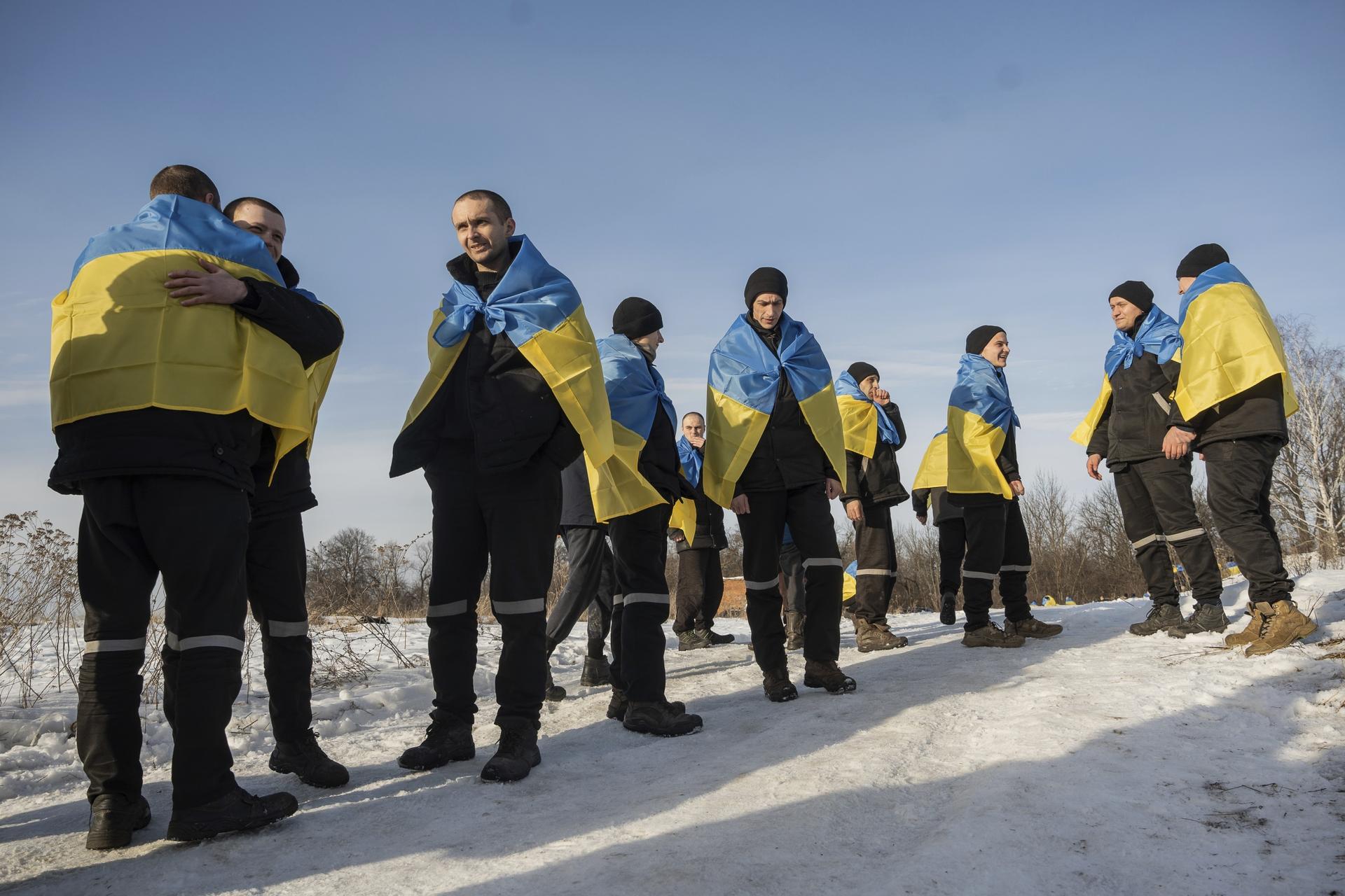A group of men wrapped around the national flag of Ukraine standing in the cold