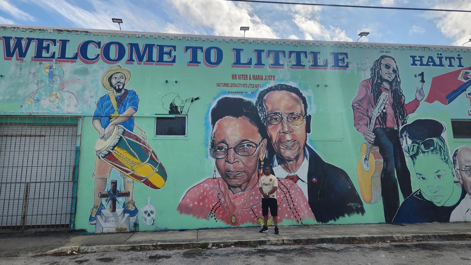 Winnick Blaine poses in front of the mural that features his grandparents, Maria and Viter Juste, who are considered to be the founders of Little Haiti in Miami.